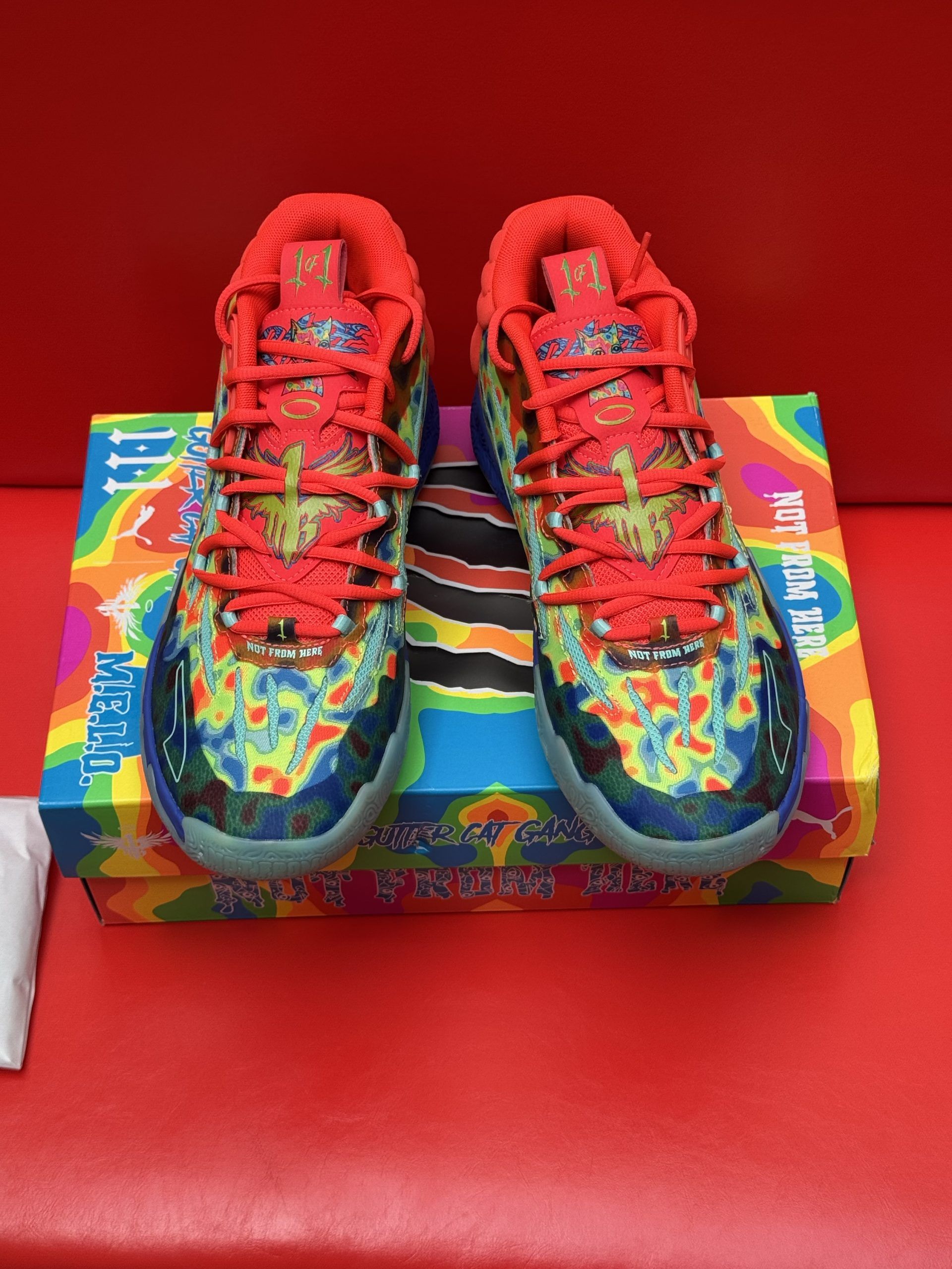 Colorful Puma sneakers with a matching box on a red background.