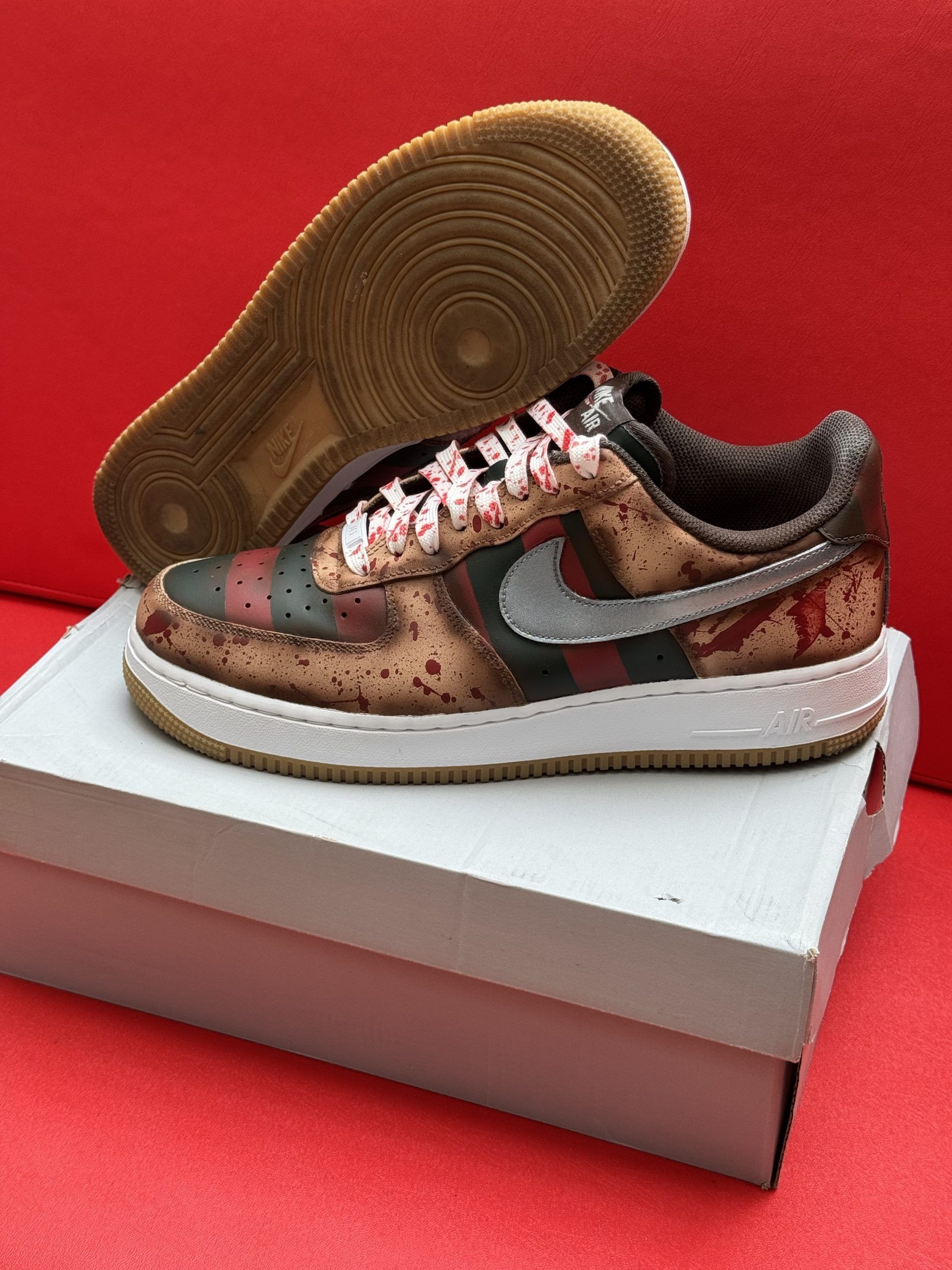 Custom Nike Air Force 1 sneakers with Freddy Krueger design on white box, red background.