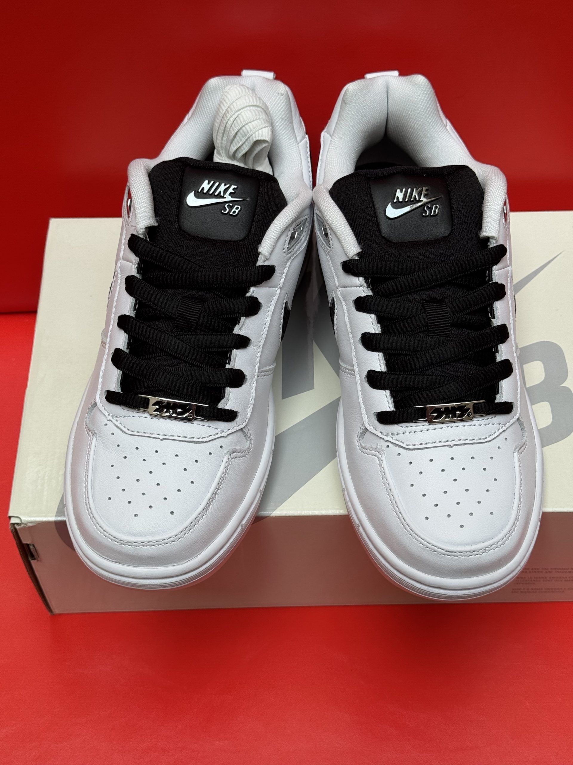 White Nike SB sneakers with black accents on box, sole visible.