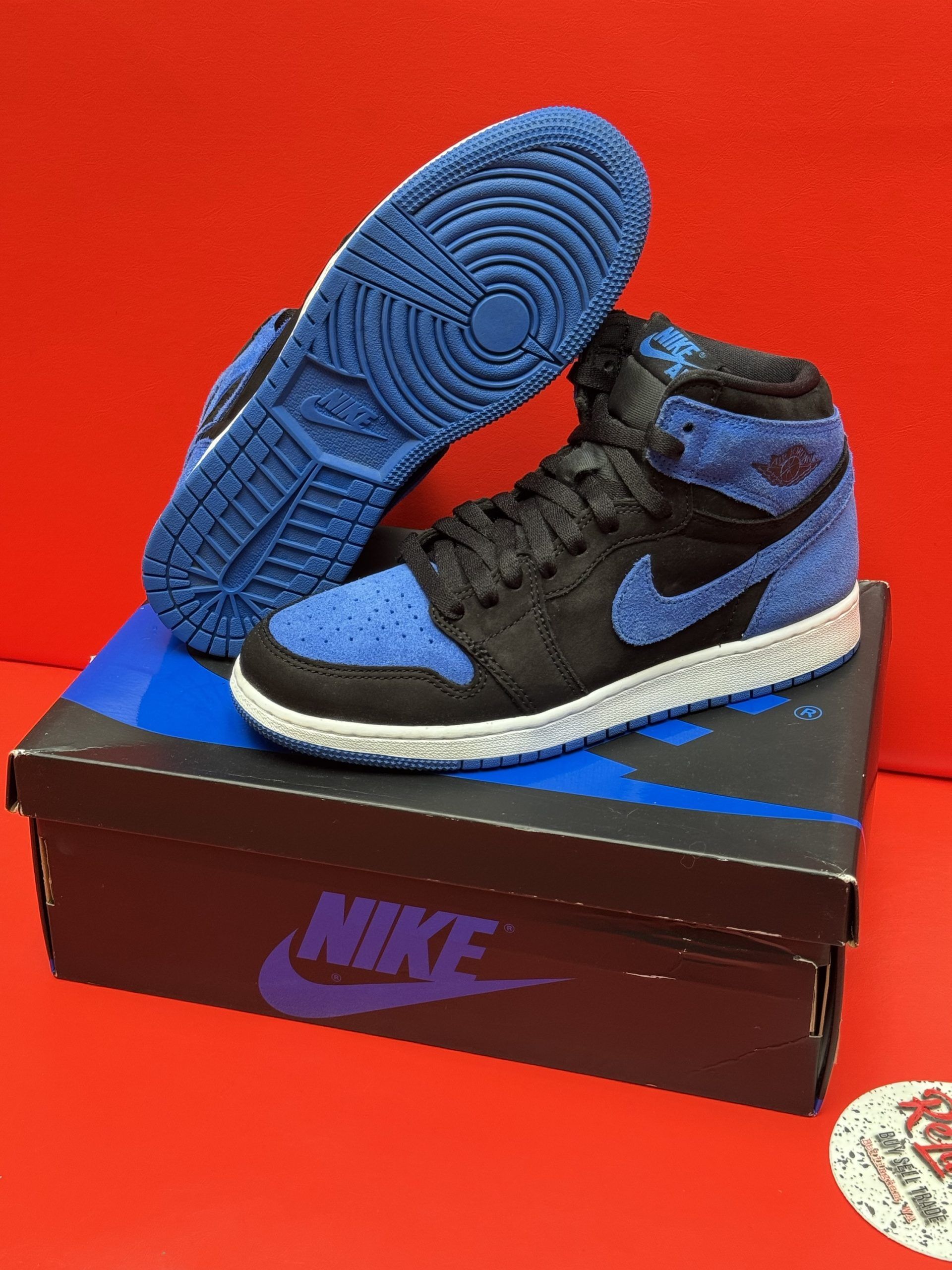 Air Jordan 1 High OG sneaker, blue and black, displayed on the box with blue sole.