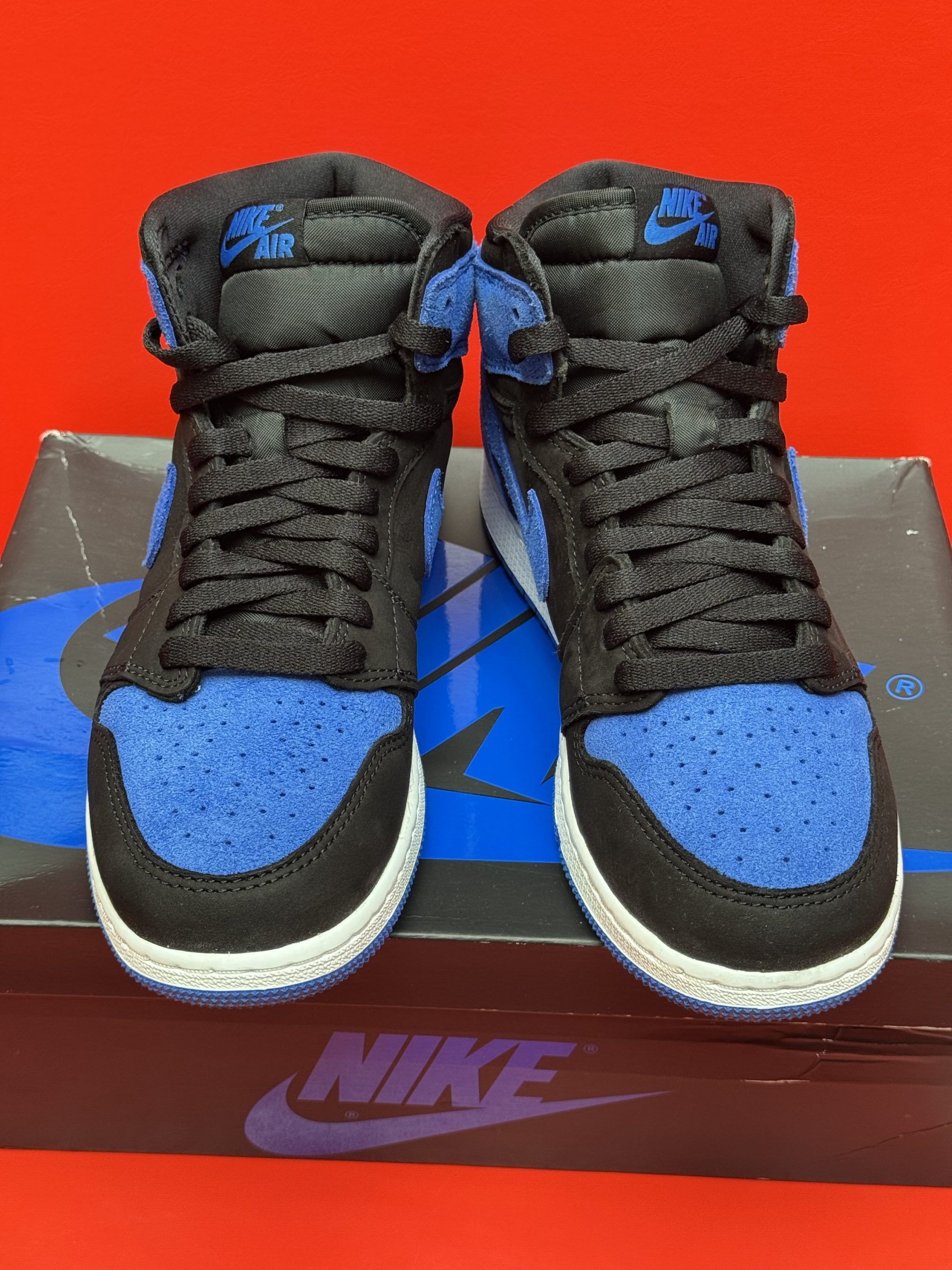 Air Jordan 1 High OG sneaker, blue and black, displayed on the box with blue sole.