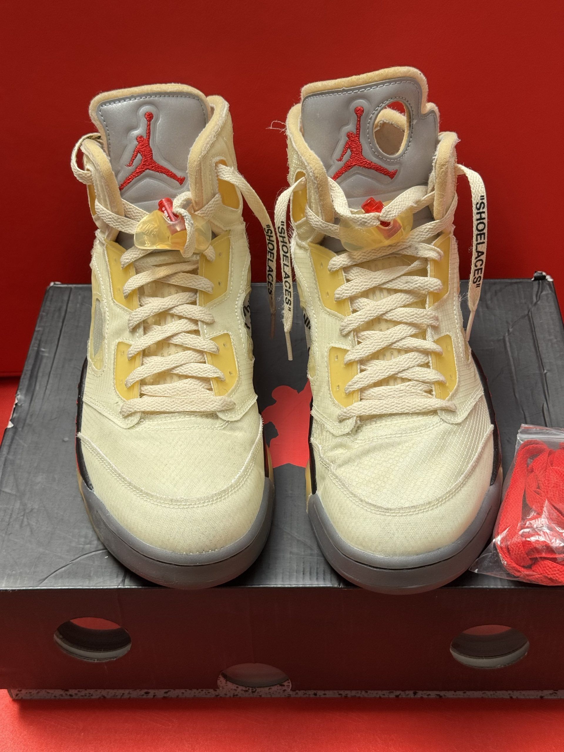 Off-White x Air Jordan 5 sneakers on a box. Off-white canvas with red accents, translucent sole, red laces.