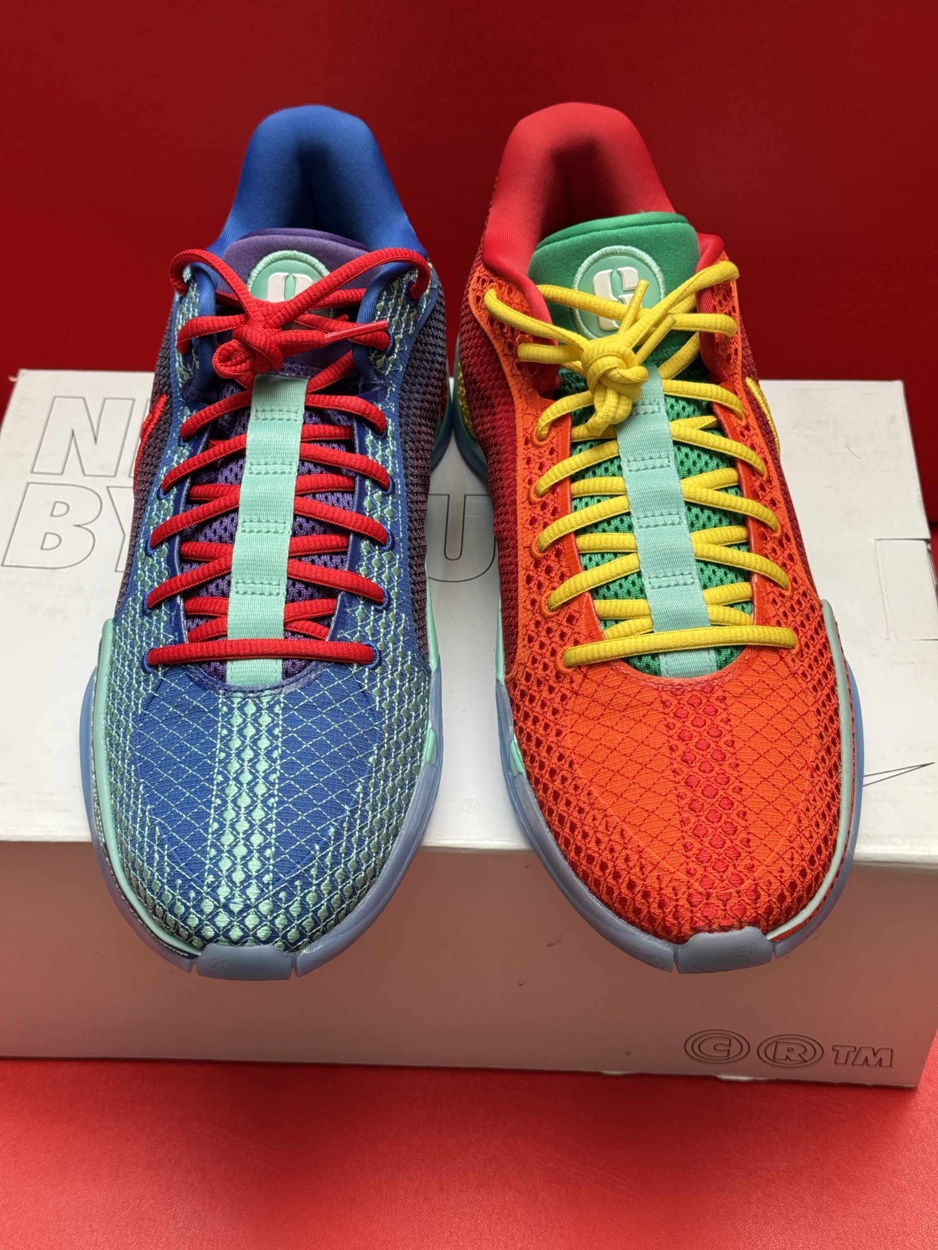 Red and yellow Nike sneaker on a box, with a light blue sole.