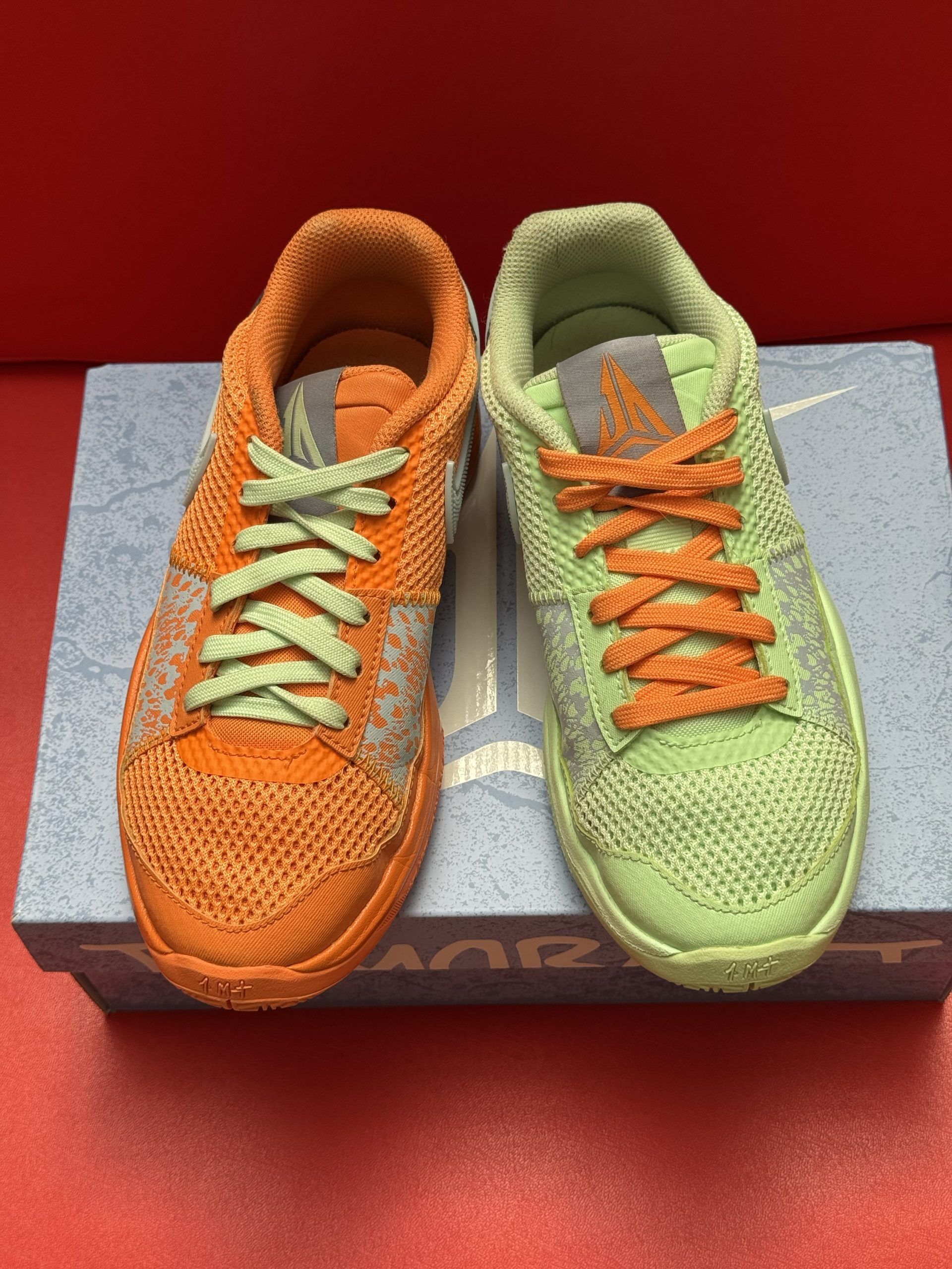 Lime green Ja Morant Nike basketball sneaker on gray box with orange sole.