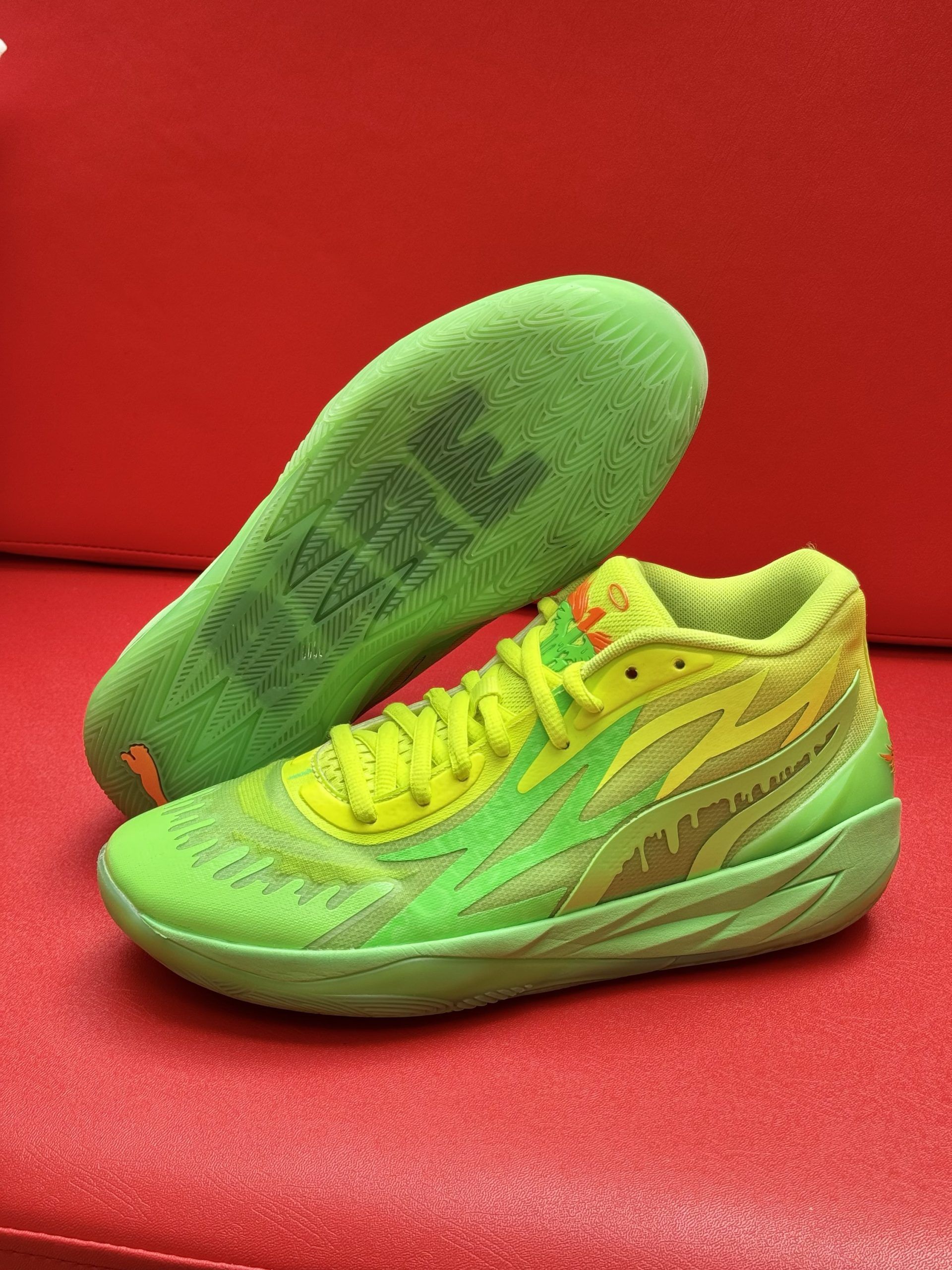 Bright green and yellow basketball shoe on red surface, with green sole showing 