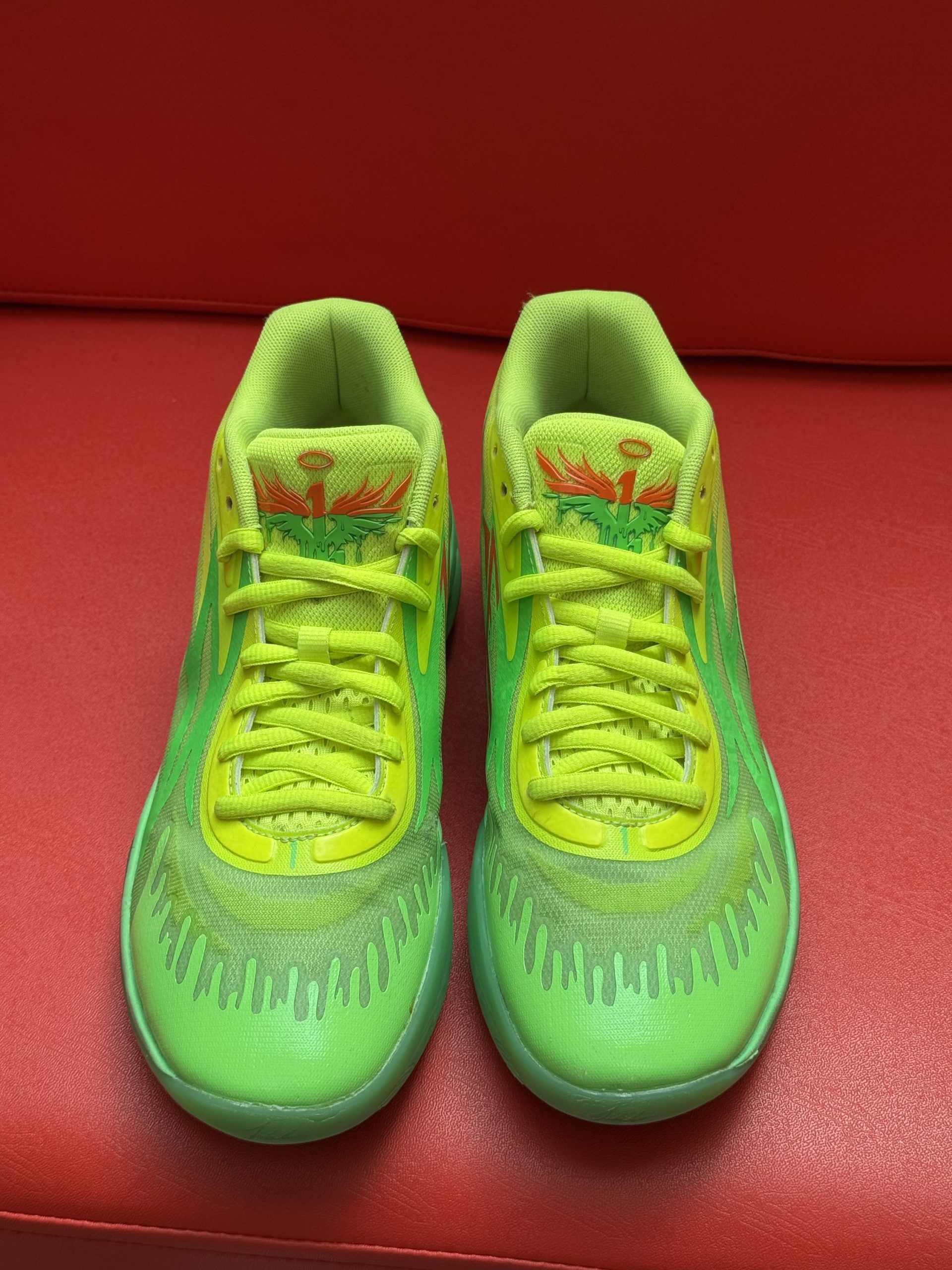 Bright green and yellow basketball shoe on red surface, with green sole showing 