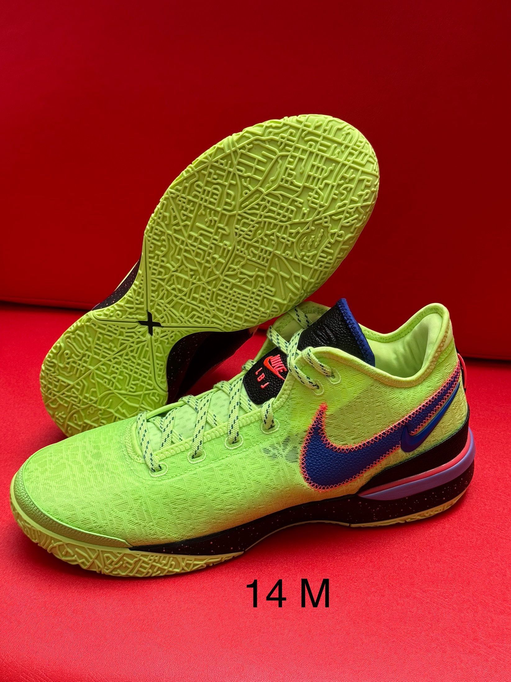Bright green and blue Nike basketball shoes on a red background. Size 14 M visible.