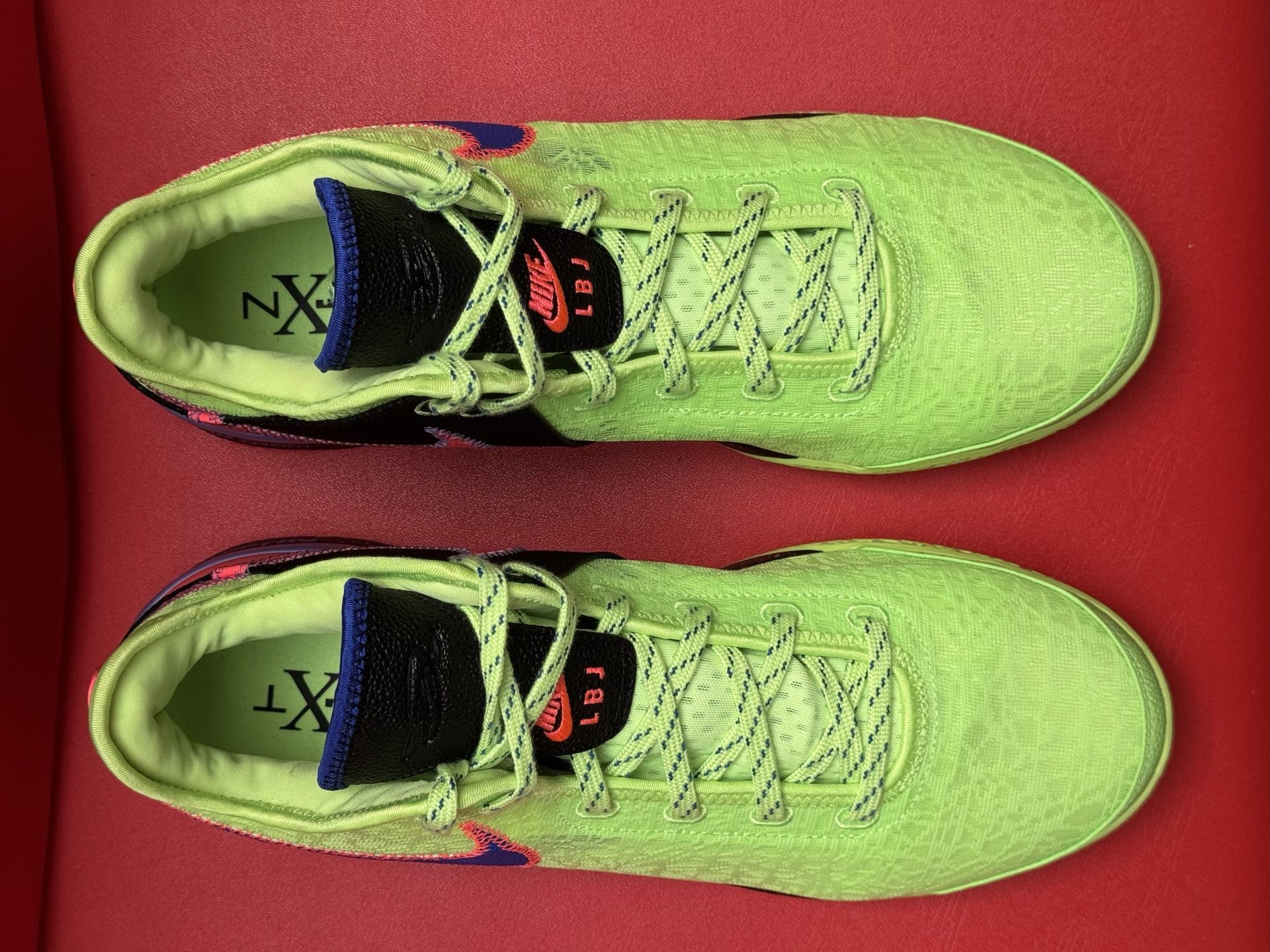 Bright green and blue Nike basketball shoes on a red background. Size 14 M visible.