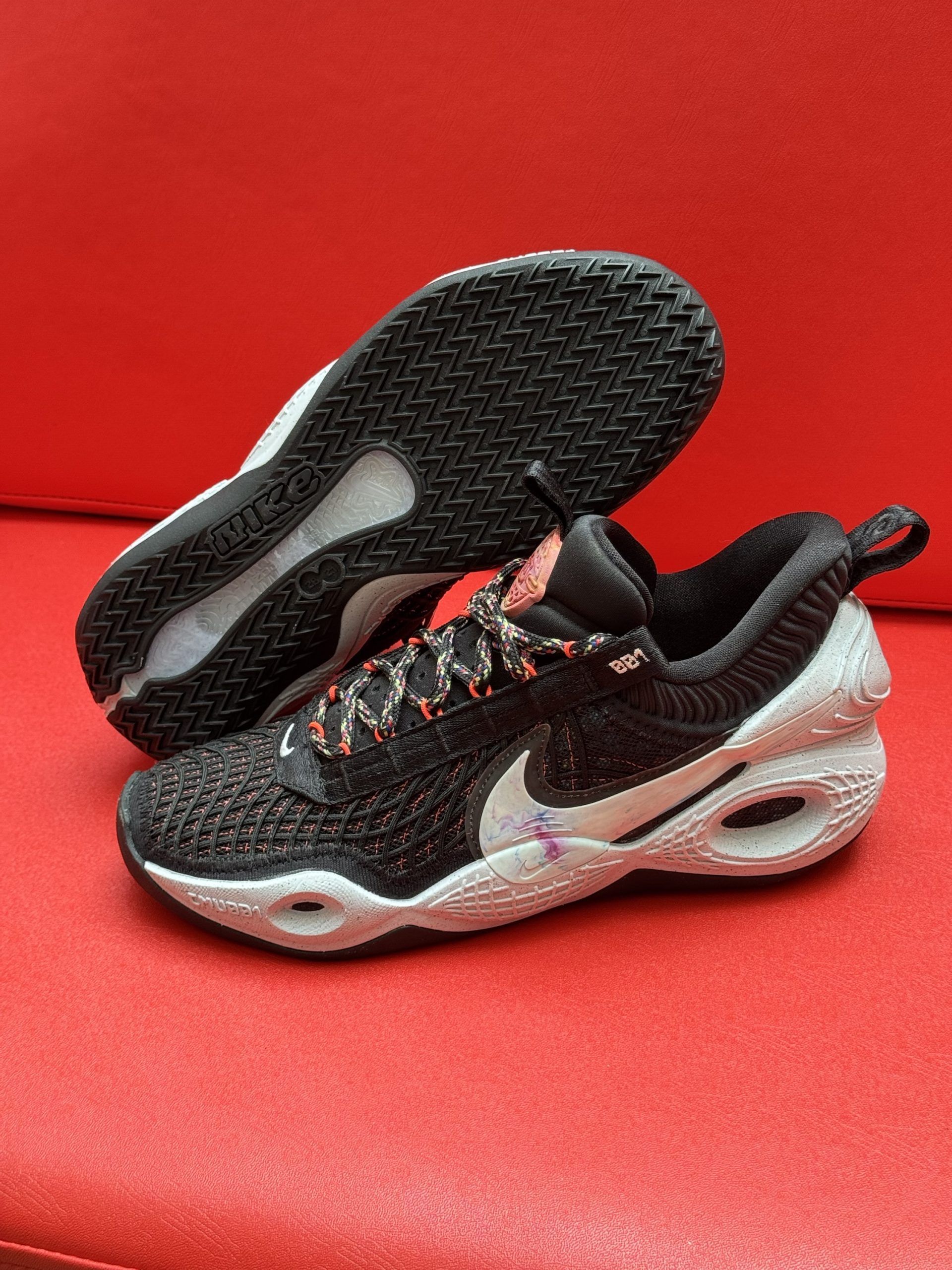 Black Nike sneakers with white accents on a red surface.