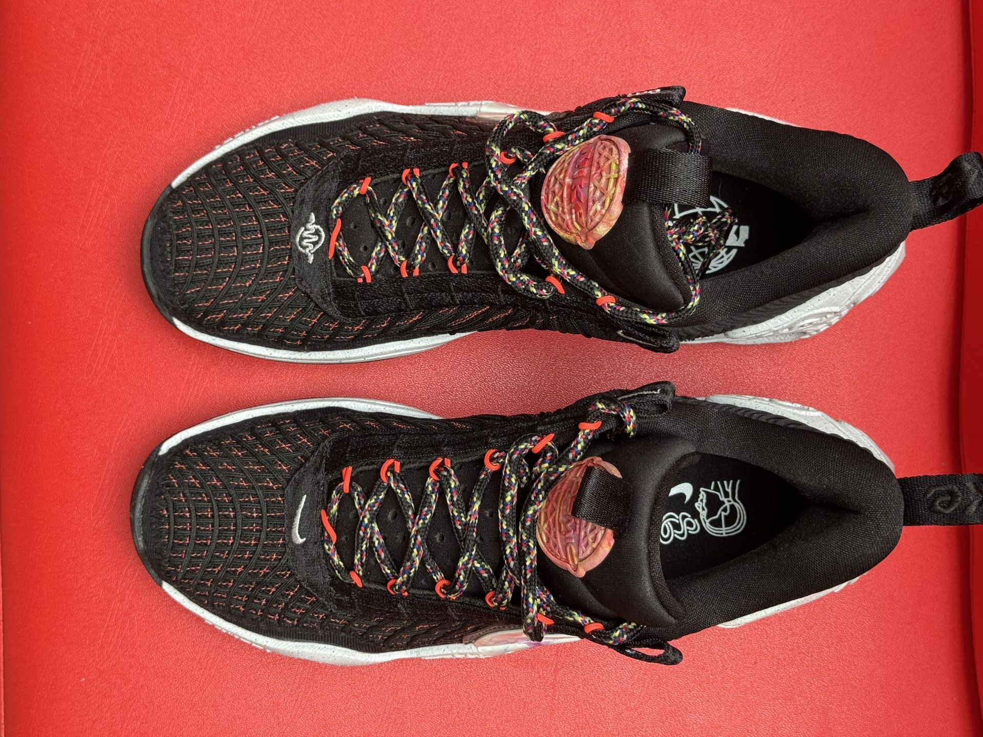 Black Nike sneakers with white accents on a red surface.