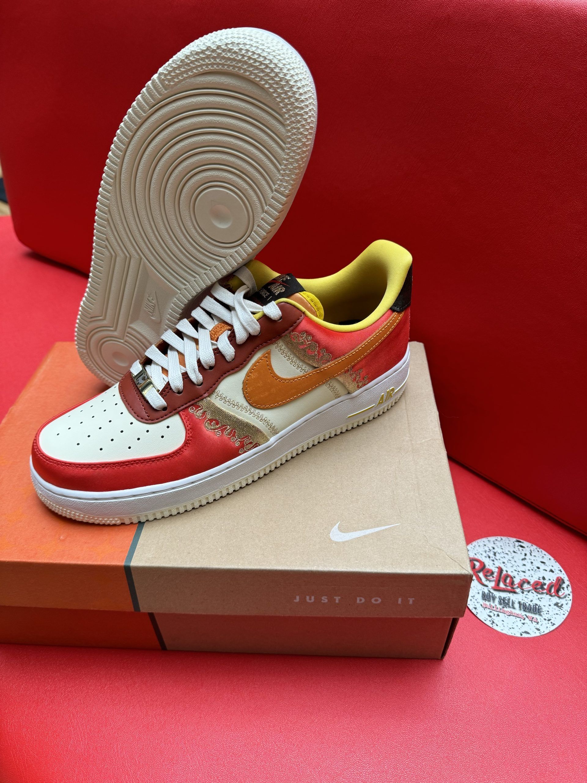 Nike Air Force 1 sneaker on a box, with a tan sole and red, orange, and tan upper.