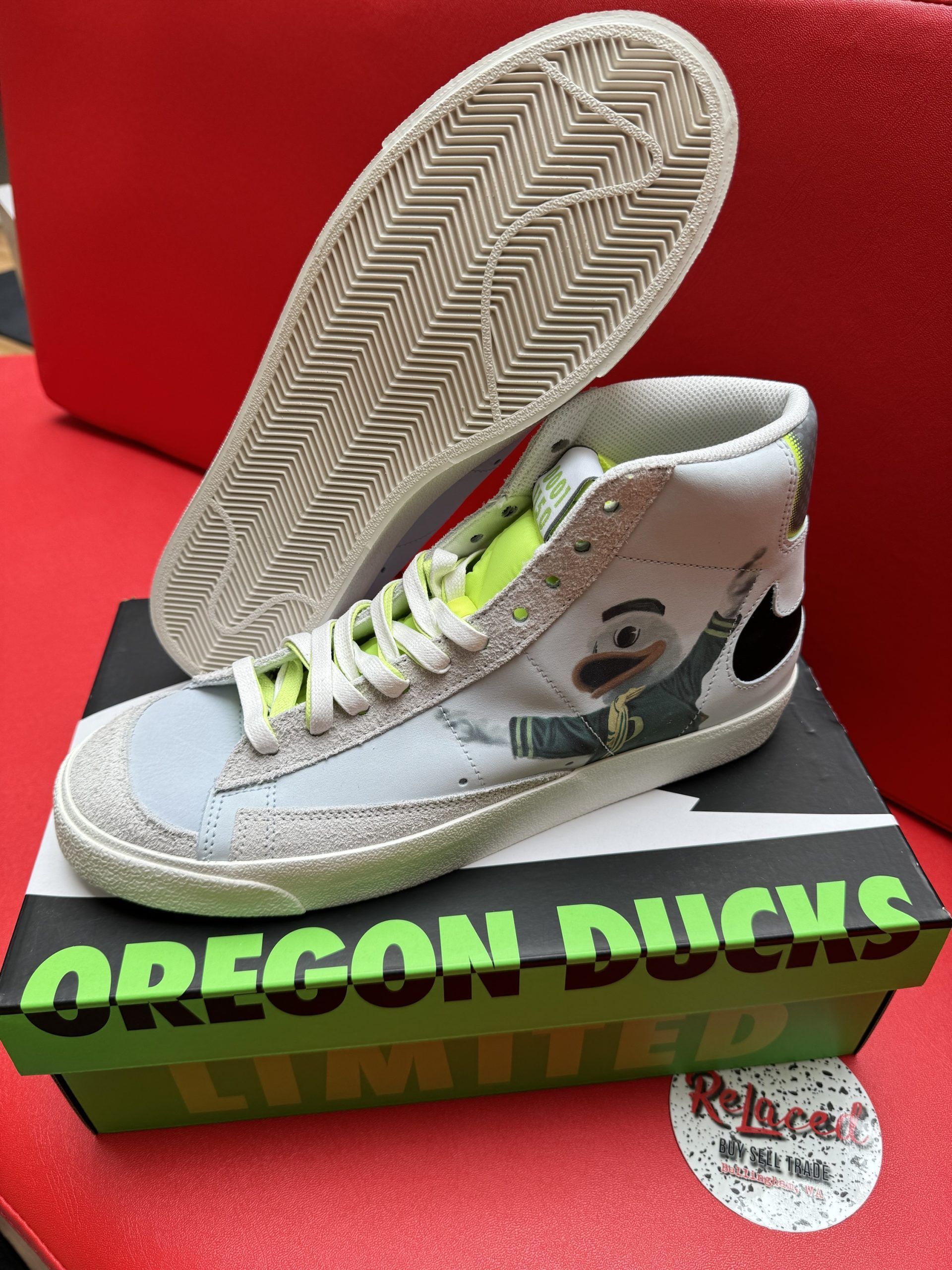 Nike Blazer mid-top sneaker on Oregon Ducks box. Light blue, white, green, cartoon graphic, black Nike logo, red backdrop.