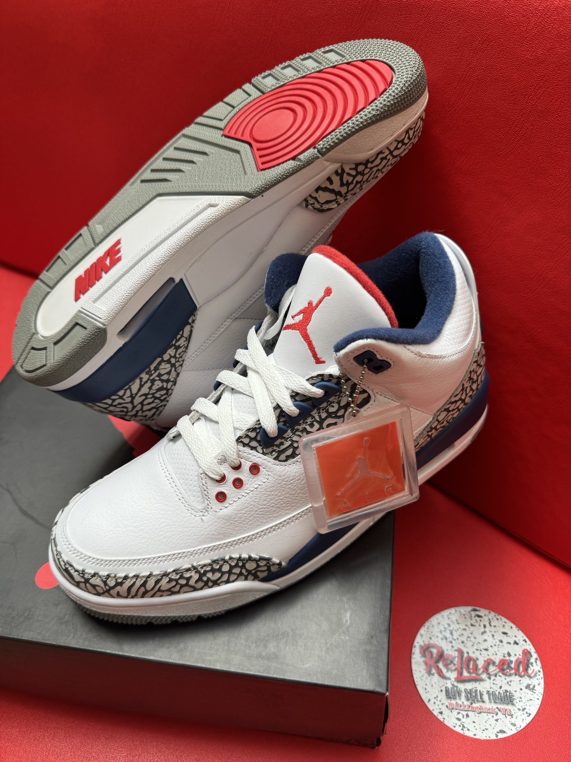White, blue, and red Air Jordan 3 sneakers with elephant print, resting on a shoebox.