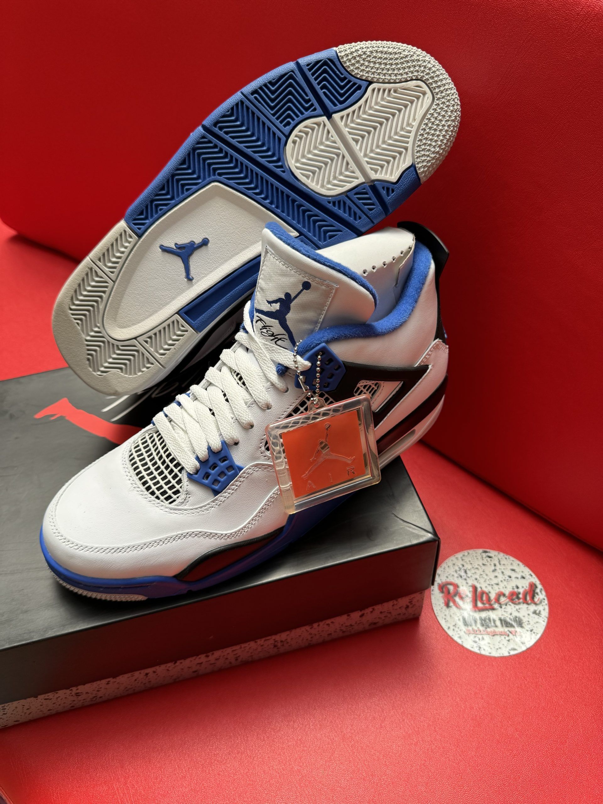 White and blue Air Jordan 4 sneaker, sole visible, on shoe box.