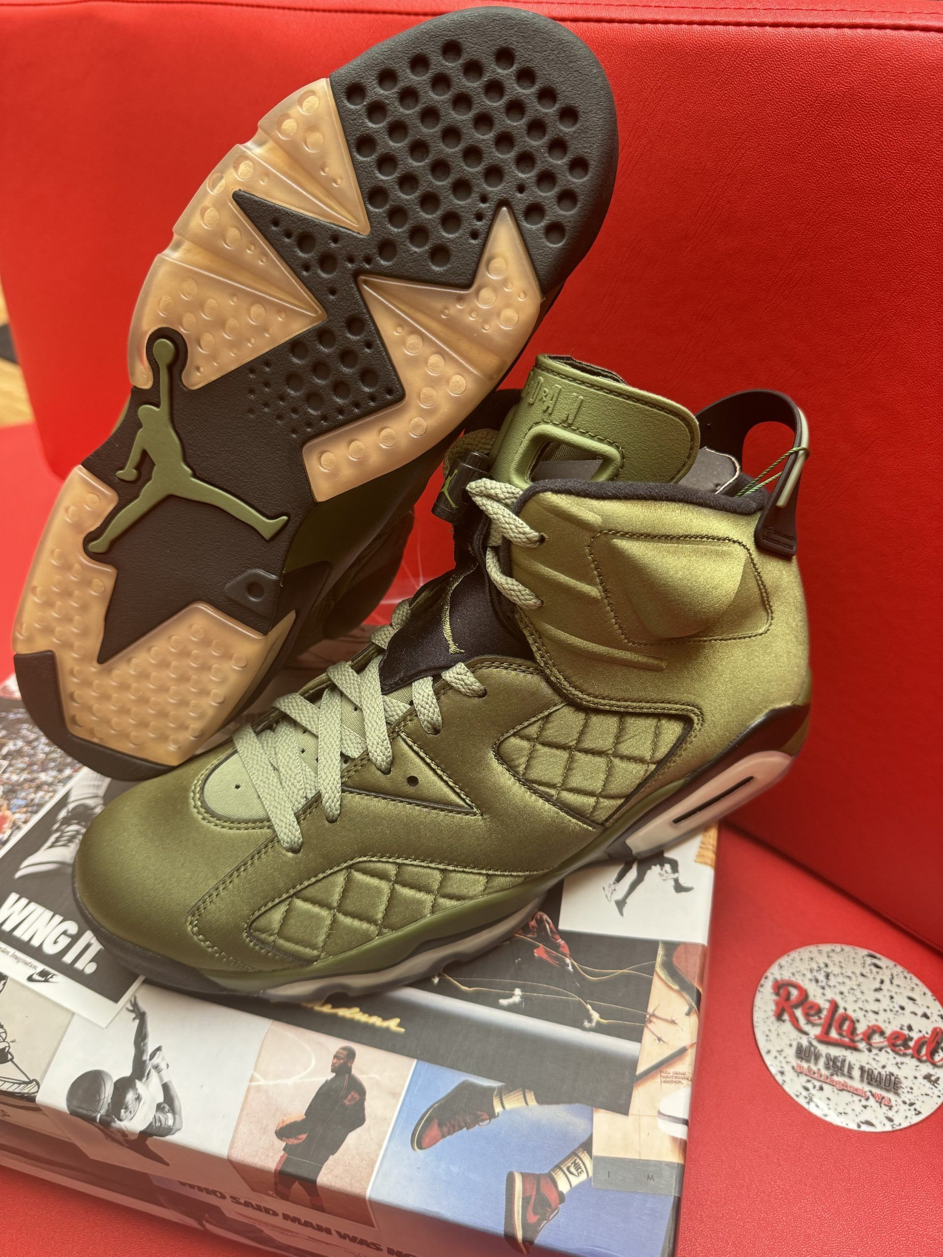 Olive green Air Jordan 6 sneakers on a box, with a gum sole and black accents.