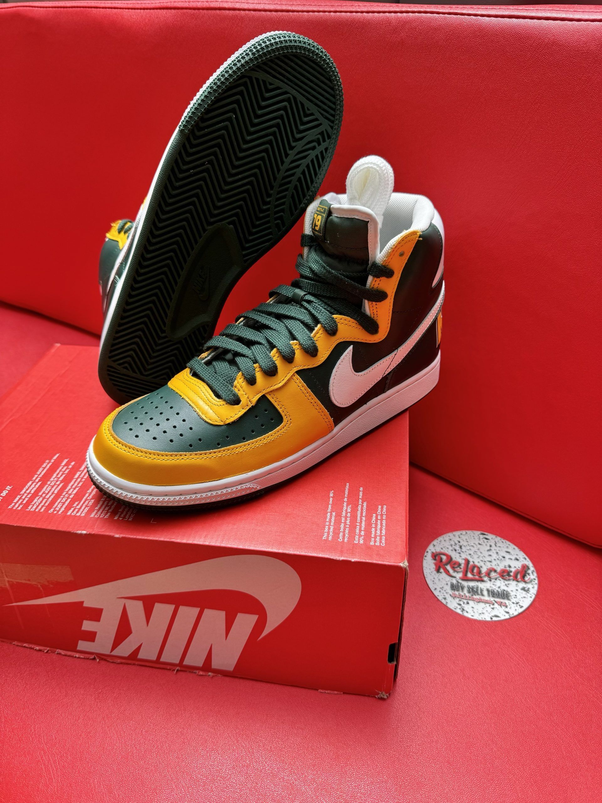 Nike high-top sneaker on a red box; black, yellow, and white color scheme.