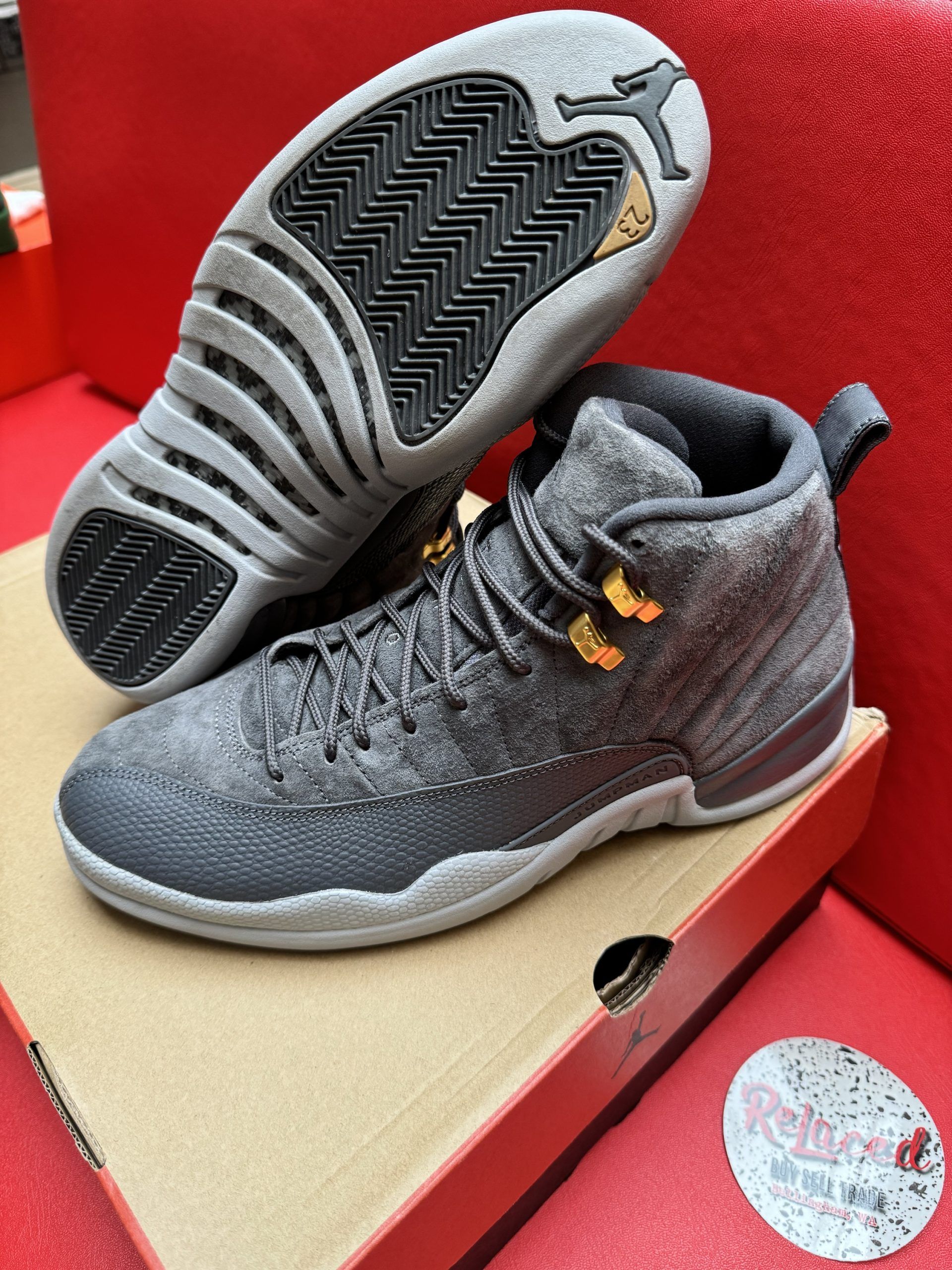 Gray Air Jordan 12 sneakers, sole visible, on a cardboard box.