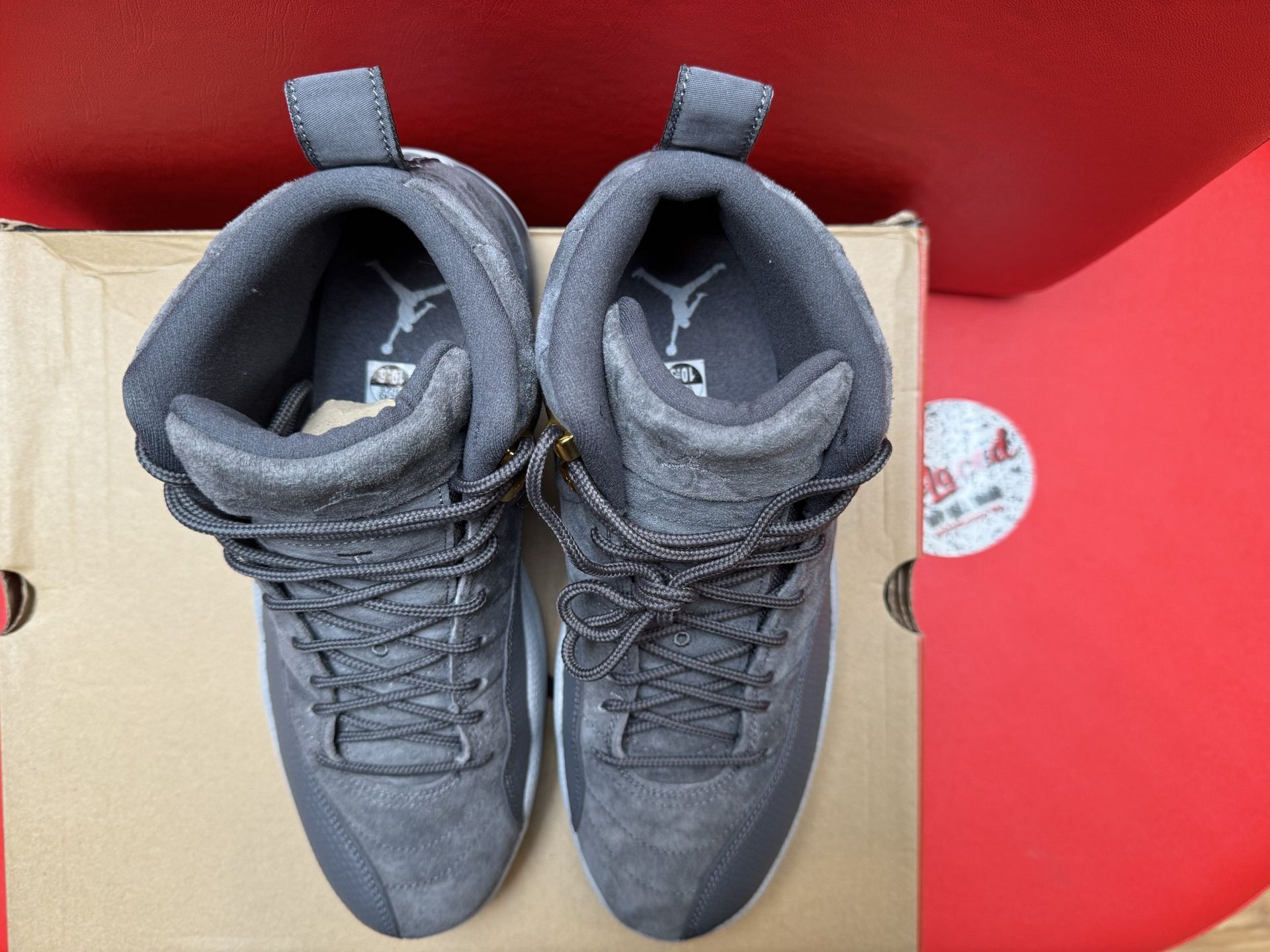 Gray Air Jordan 12 sneakers, sole visible, on a cardboard box.