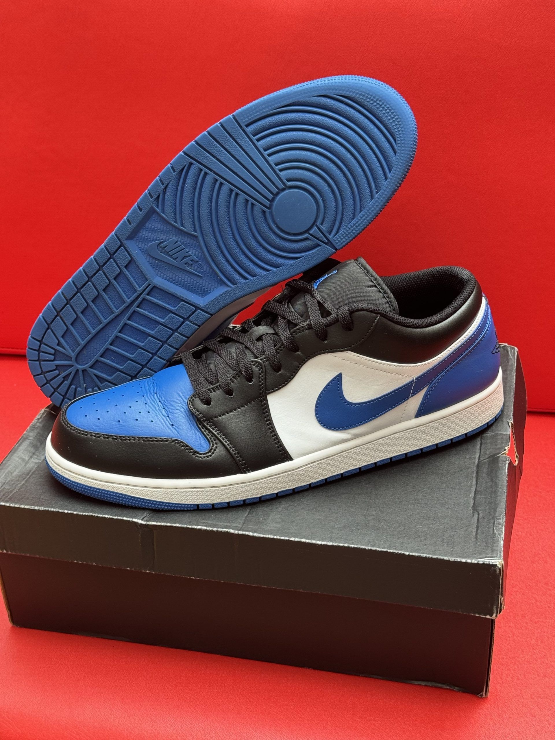 Blue, black, and white Air Jordan 1 Low sneaker on a box, sole visible.