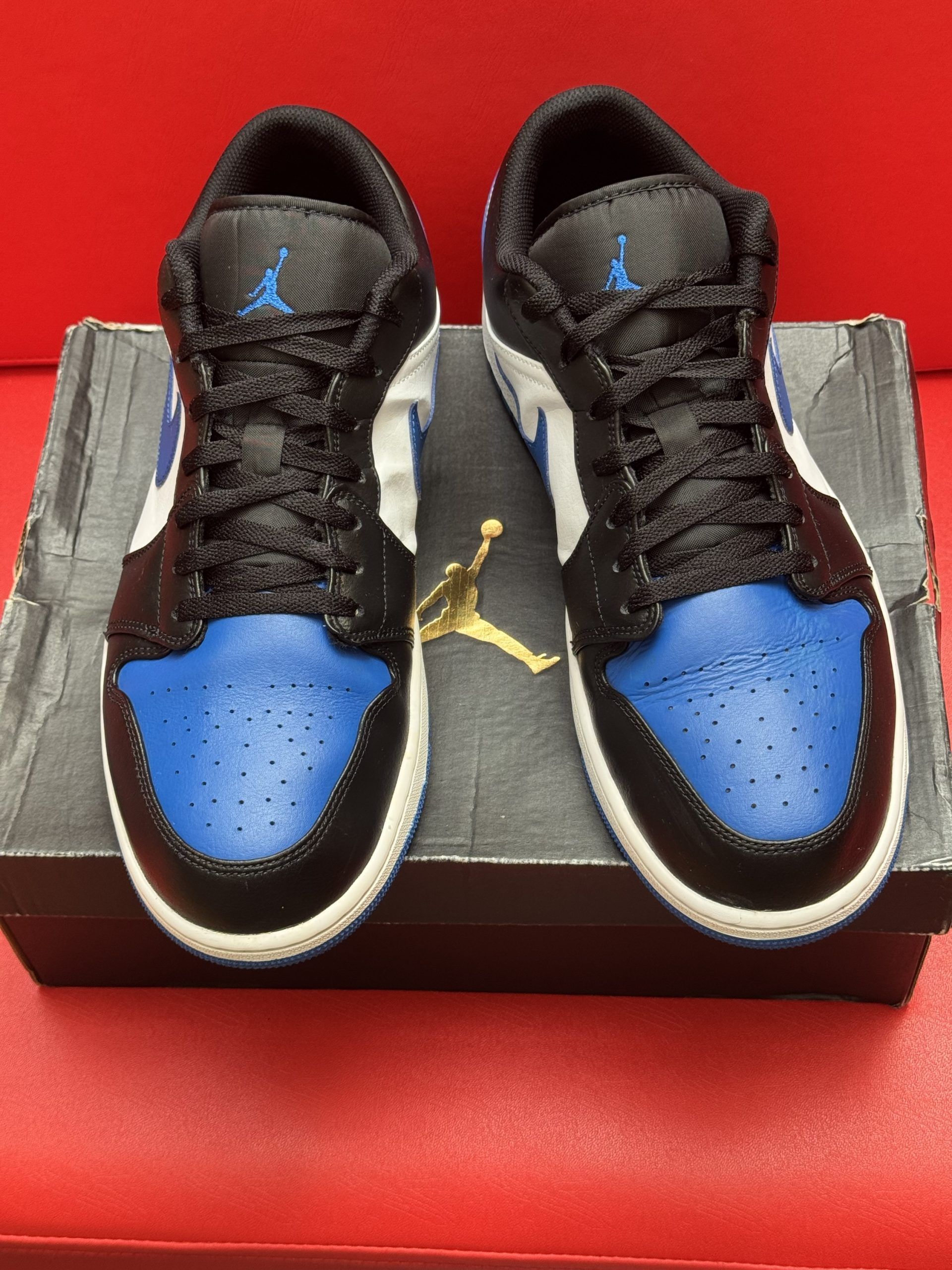 Blue, black, and white Air Jordan 1 Low sneaker on a box, sole visible.
