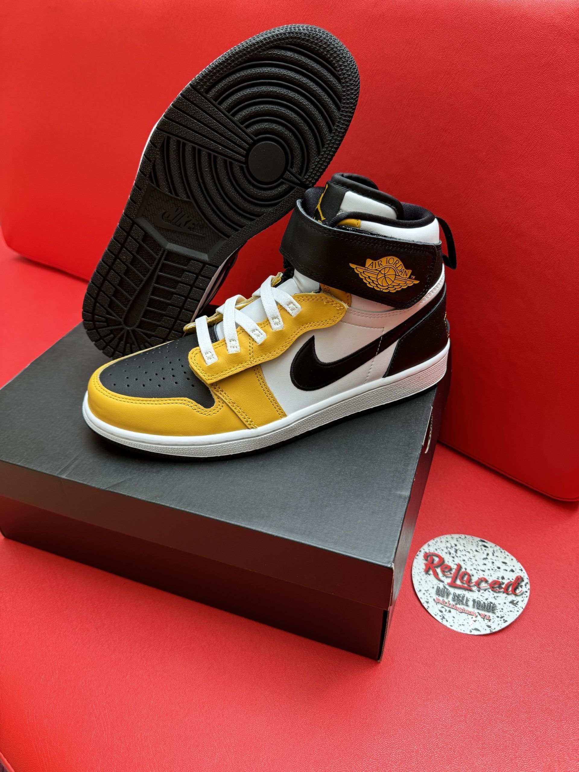 Yellow, black, and white Air Jordan 1 sneaker on a box with the sole visible.