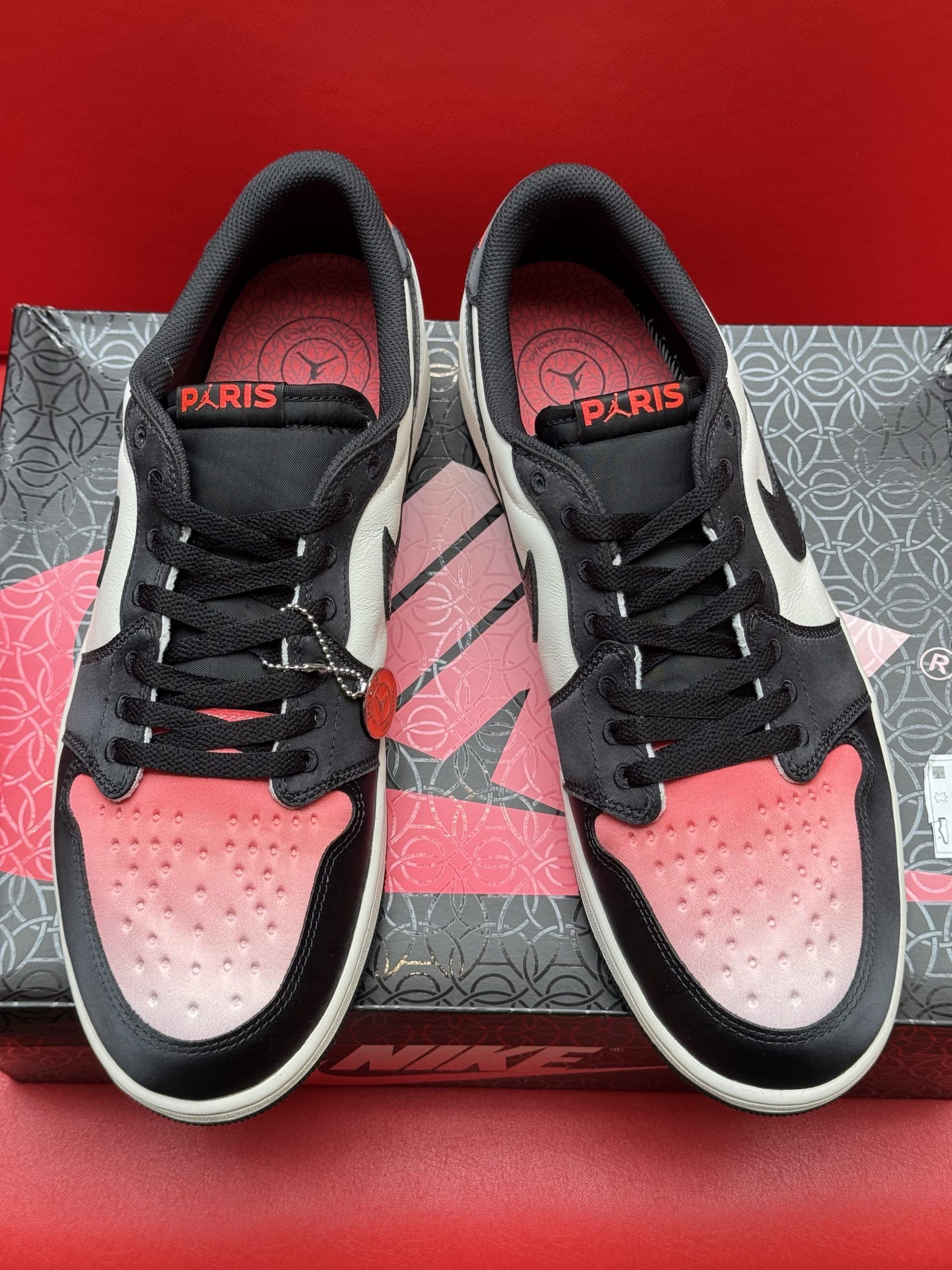 Black, red, and white Air Jordan 1 Low sneaker sits on a black shoe box. The sole is visible.