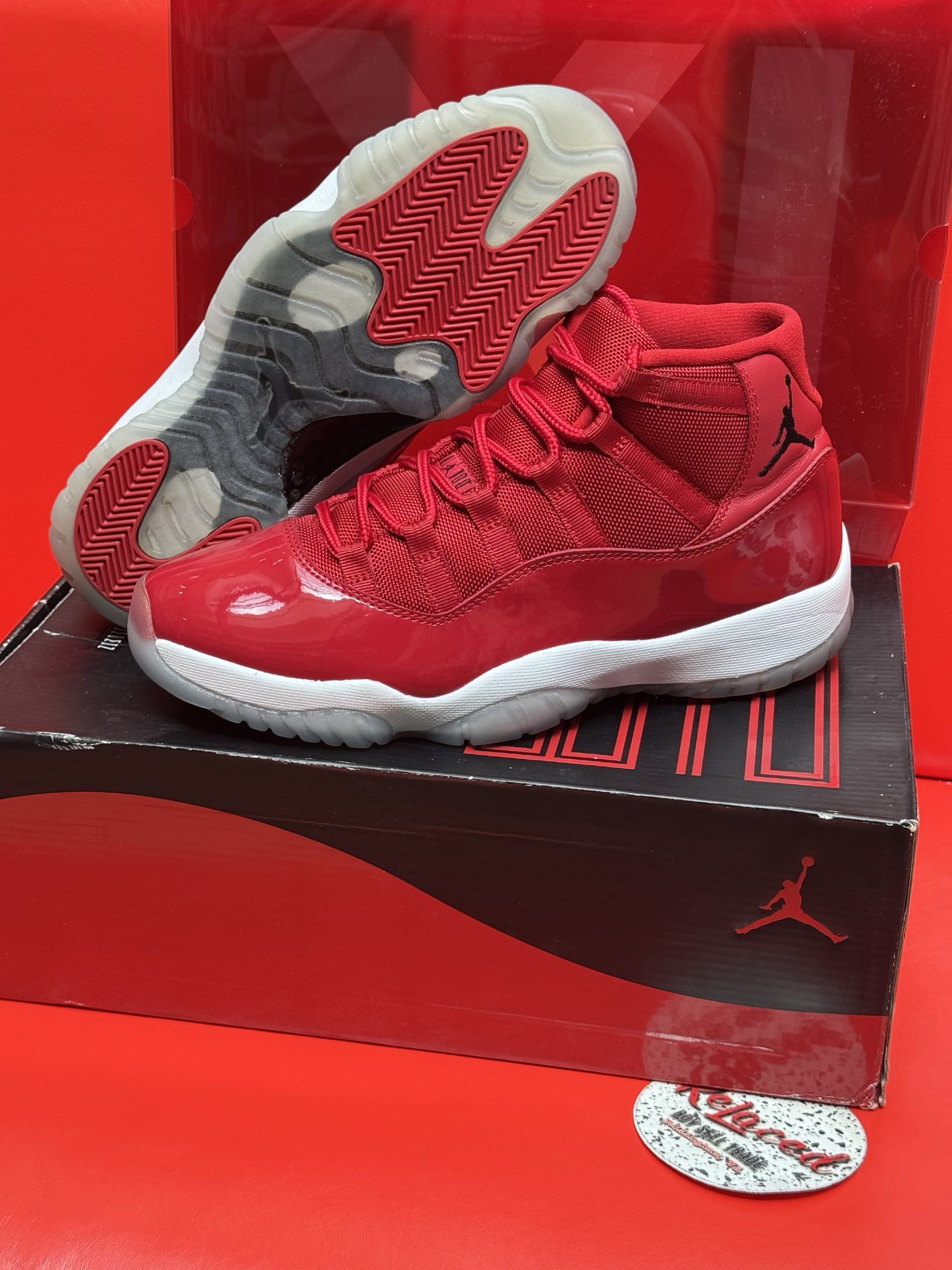 Red Air Jordan 11 sneakers on a box, with a white sole and red accents.