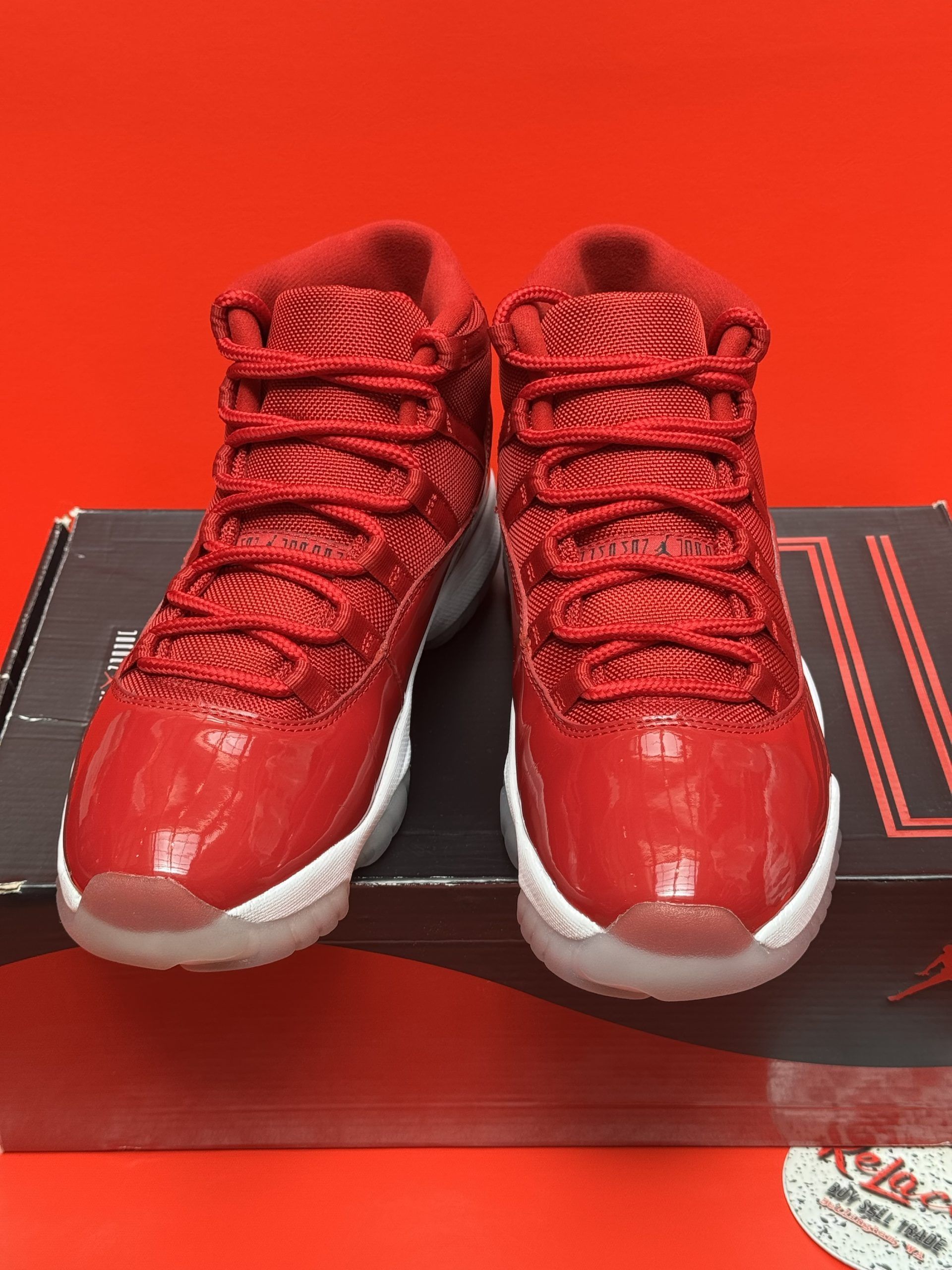 Red Air Jordan 11 sneakers on a box, with a white sole and red accents.