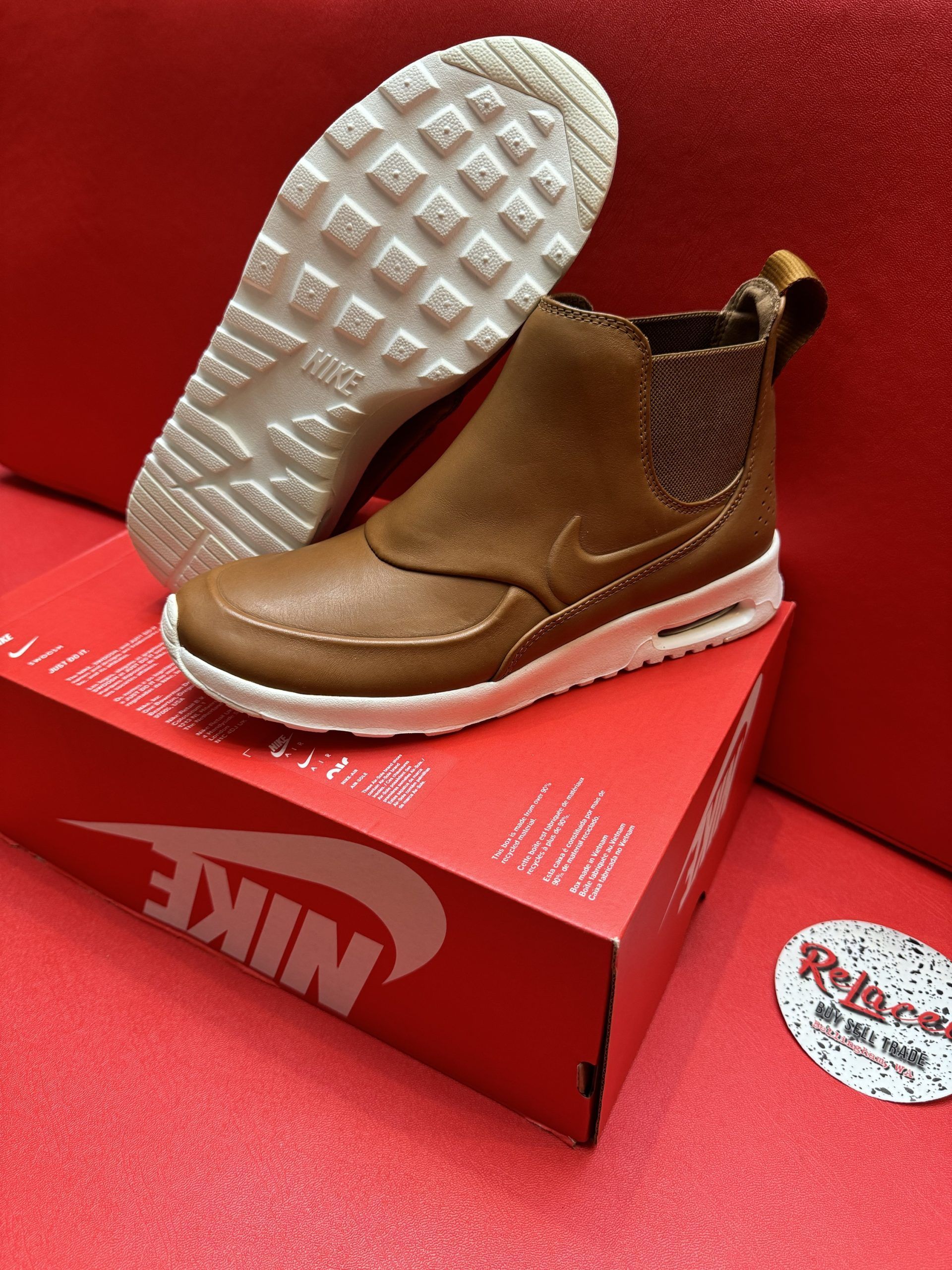 Brown Nike ankle boot on red Nike box with white sole and textured brown ankle detail.