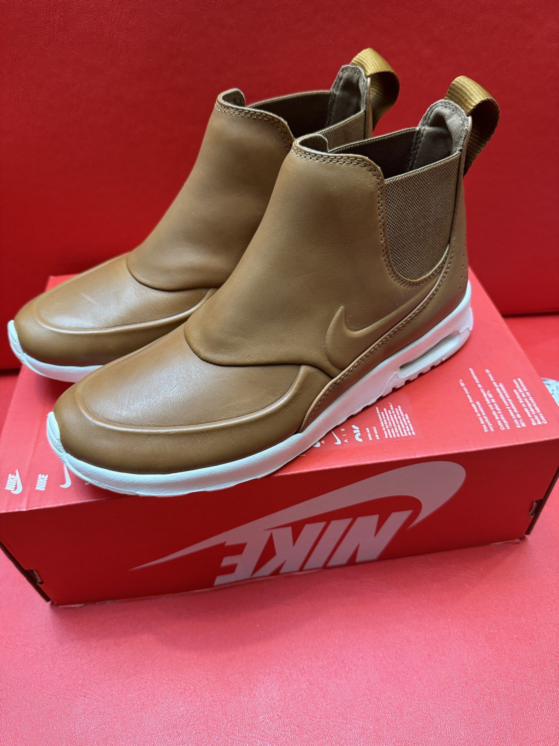 Brown Nike ankle boot on red Nike box with white sole and textured brown ankle detail.