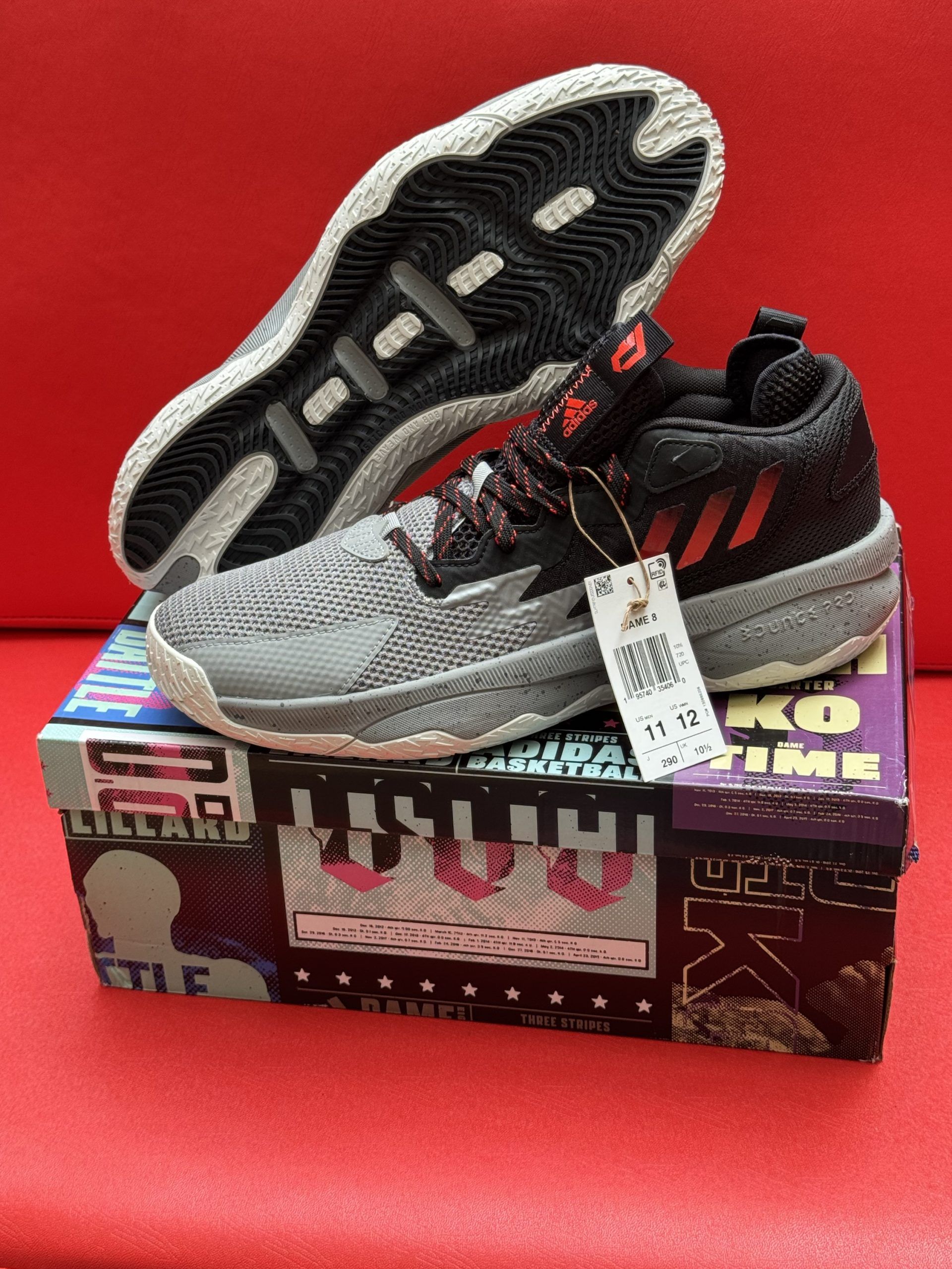 Gray and black Adidas basketball shoes with a price tag, sitting on a colorful shoebox.