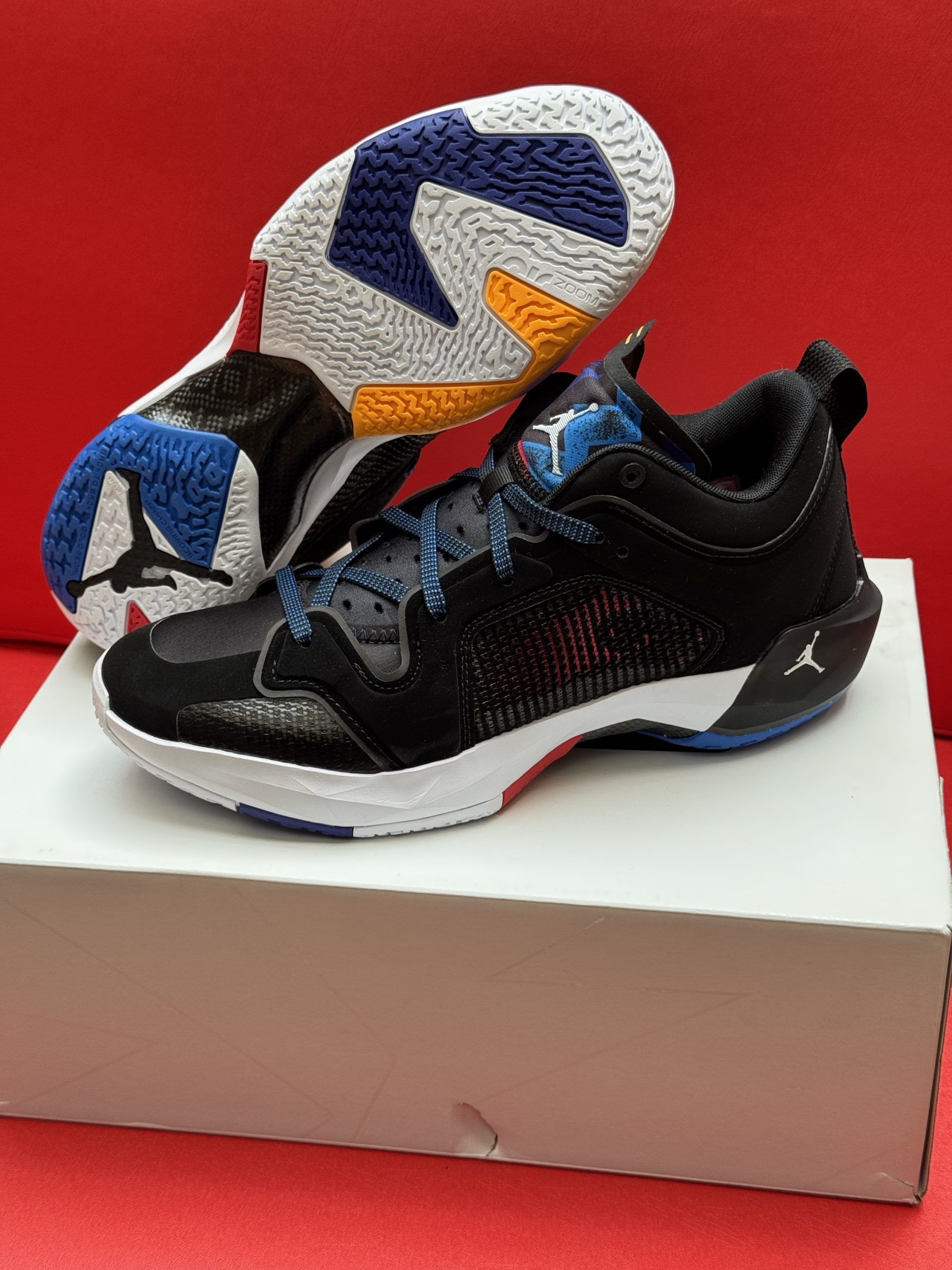 Black and blue Jordan basketball shoe on a white box, with the sole of a second shoe visible behind.