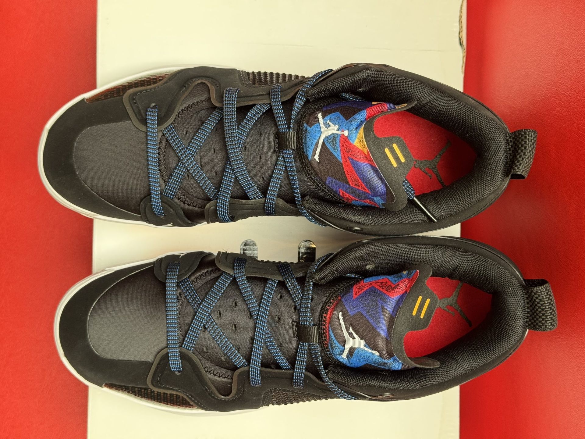 Black and blue Jordan basketball shoe on a white box, with the sole of a second shoe visible behind.