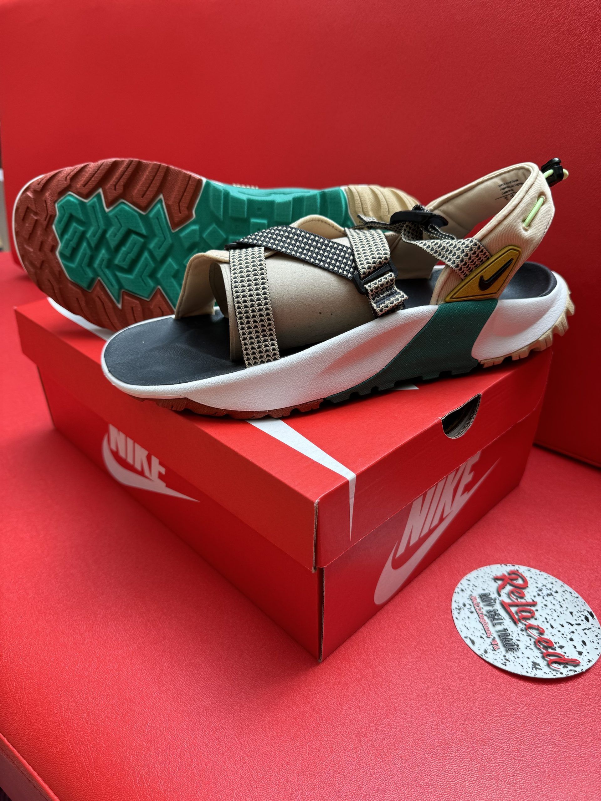 Nike sandals on a red Nike box, with a brown, green, white, and black color scheme.