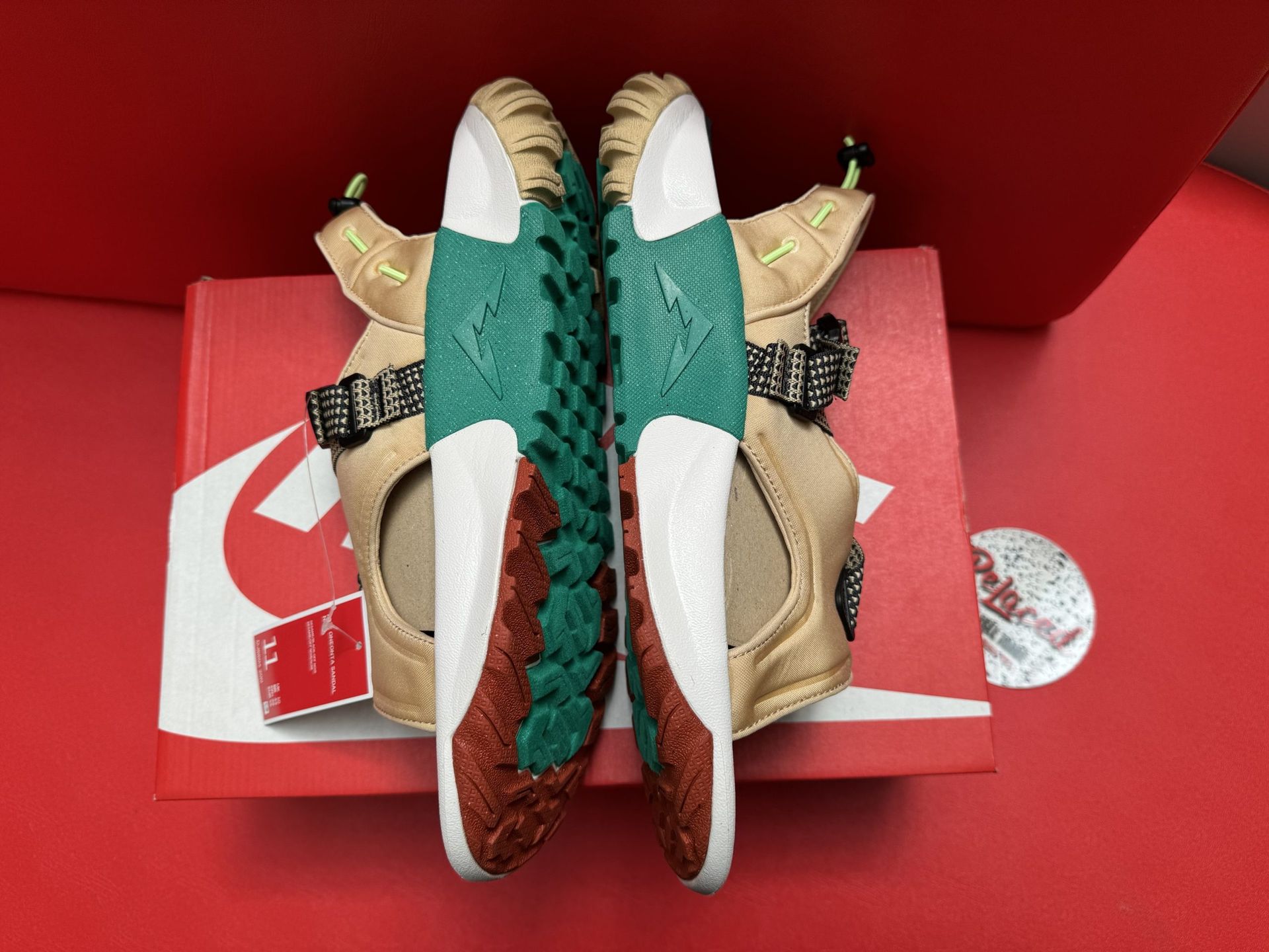 Nike sandals on a red Nike box, with a brown, green, white, and black color scheme.