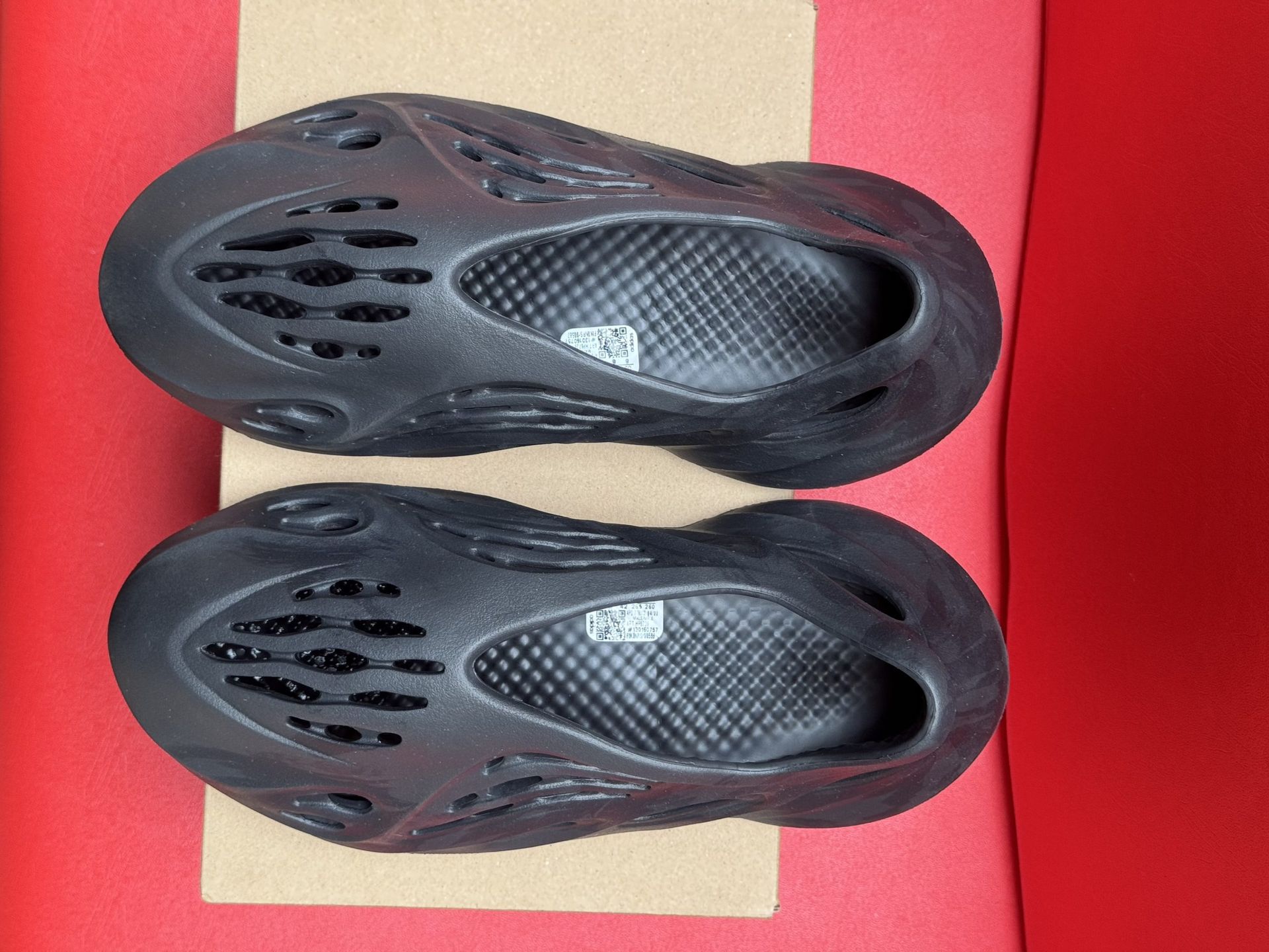 Pair of dark gray Yeezy Foam Runners inside their cardboard box labeled 