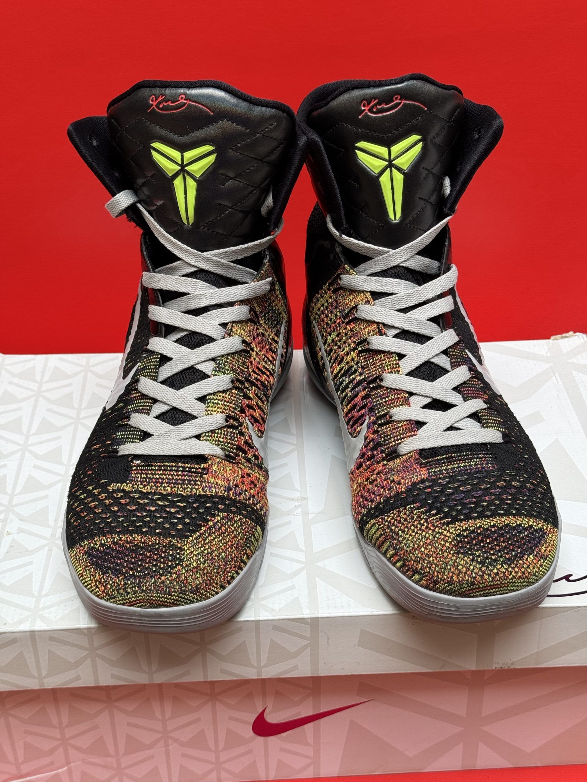 Black and gray Kobe basketball sneakers with white accents, laces, and swoosh logo on a white box.