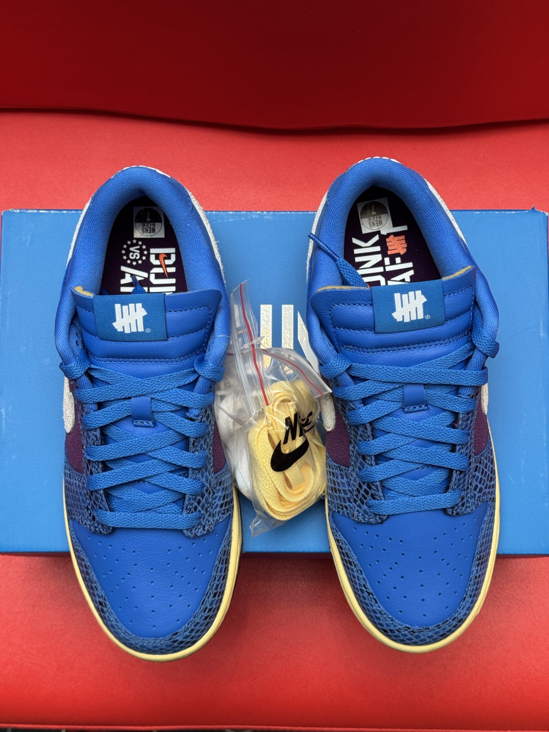 Blue Nike Dunk Low sneakers with purple accents, white swoosh, and purple sole on a blue Nike box.