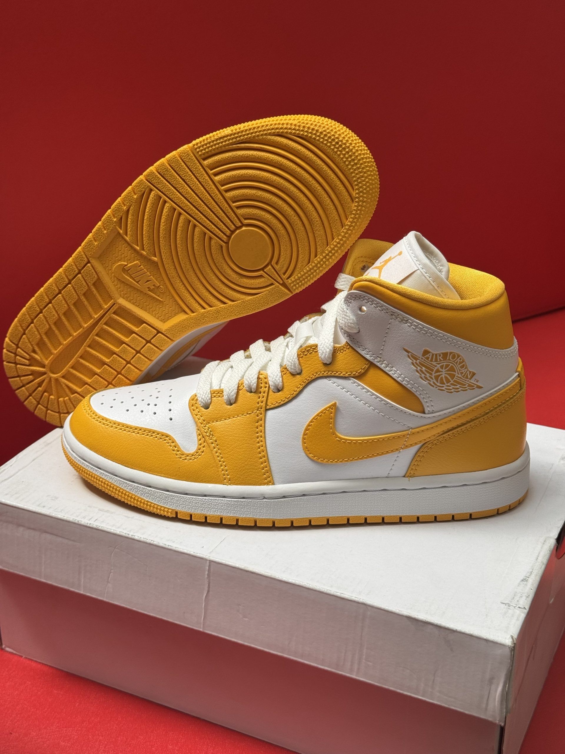 Yellow and white Air Jordan Mid sneaker on a box, with a yellow sole visible beside it.