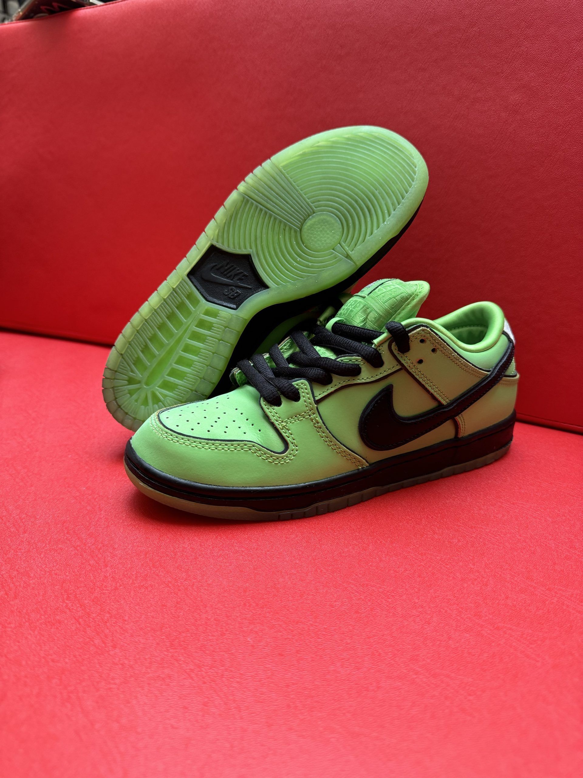 Green Nike Dunk sneakers, Powerpuff Girl Buttercup themed, on red surface.