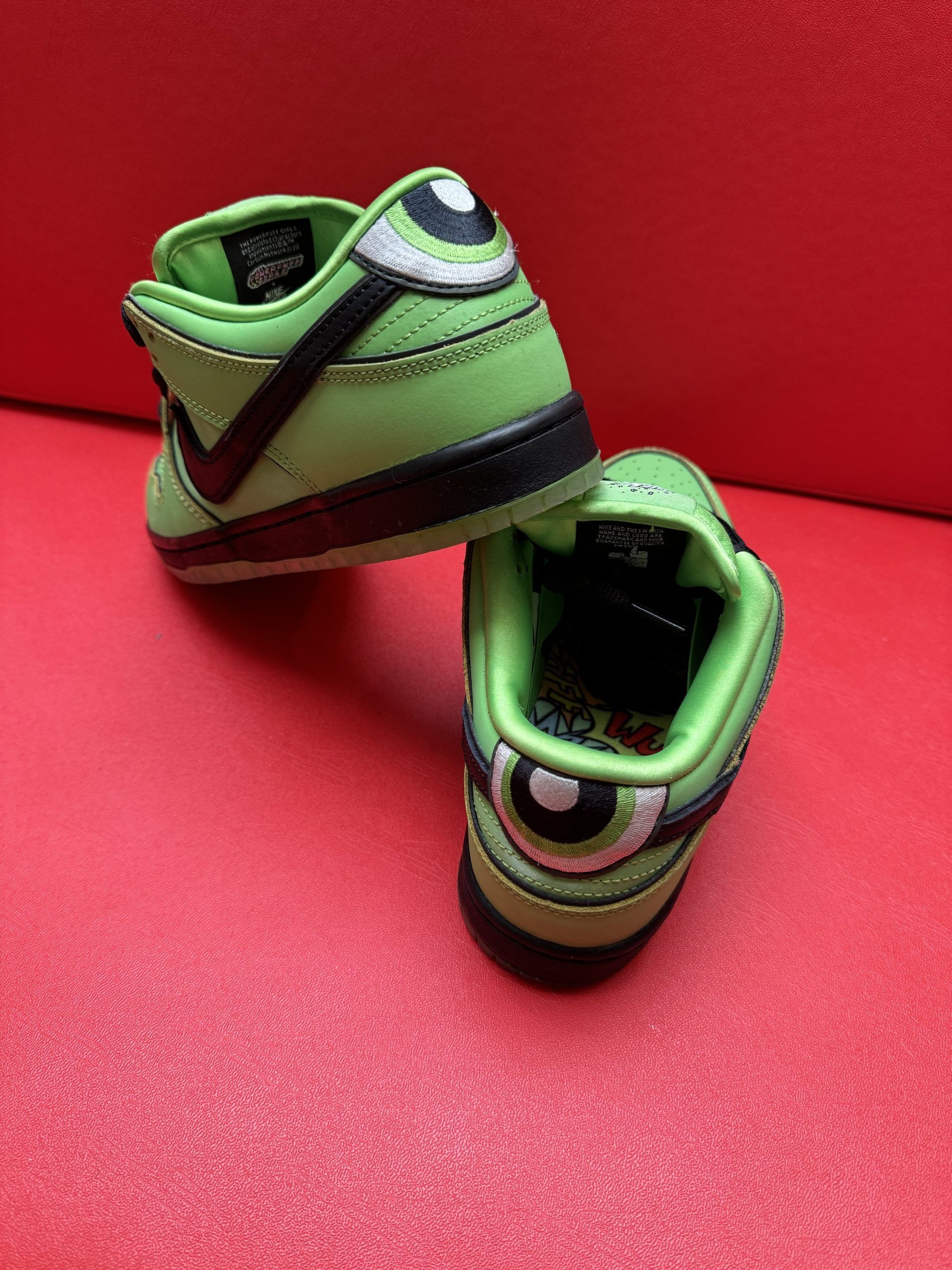 Green Nike Dunk sneakers, Powerpuff Girl Buttercup themed, on red surface.