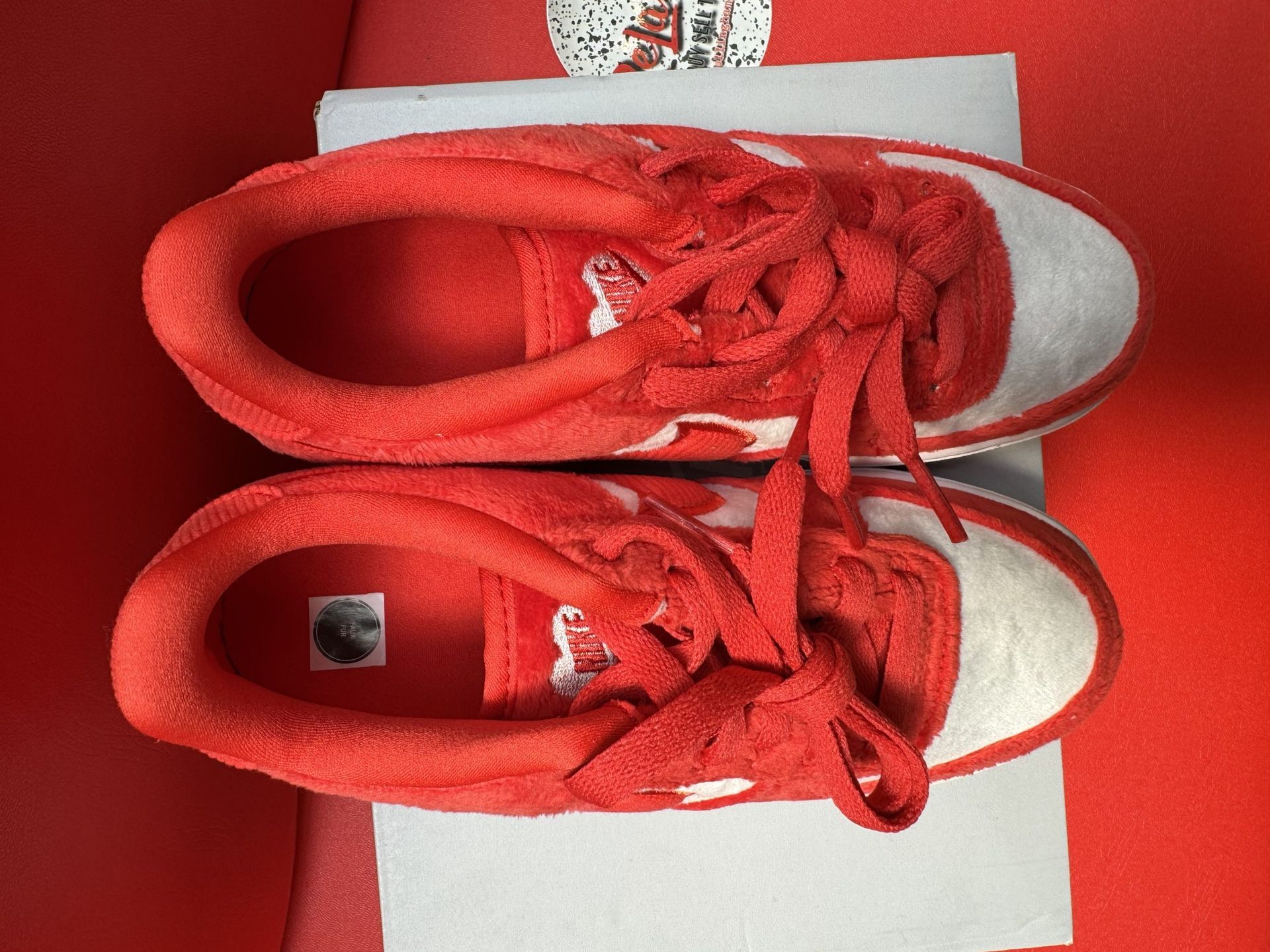 Red and white Nike Air Force 1 sneakers on a white box, red sole visible.