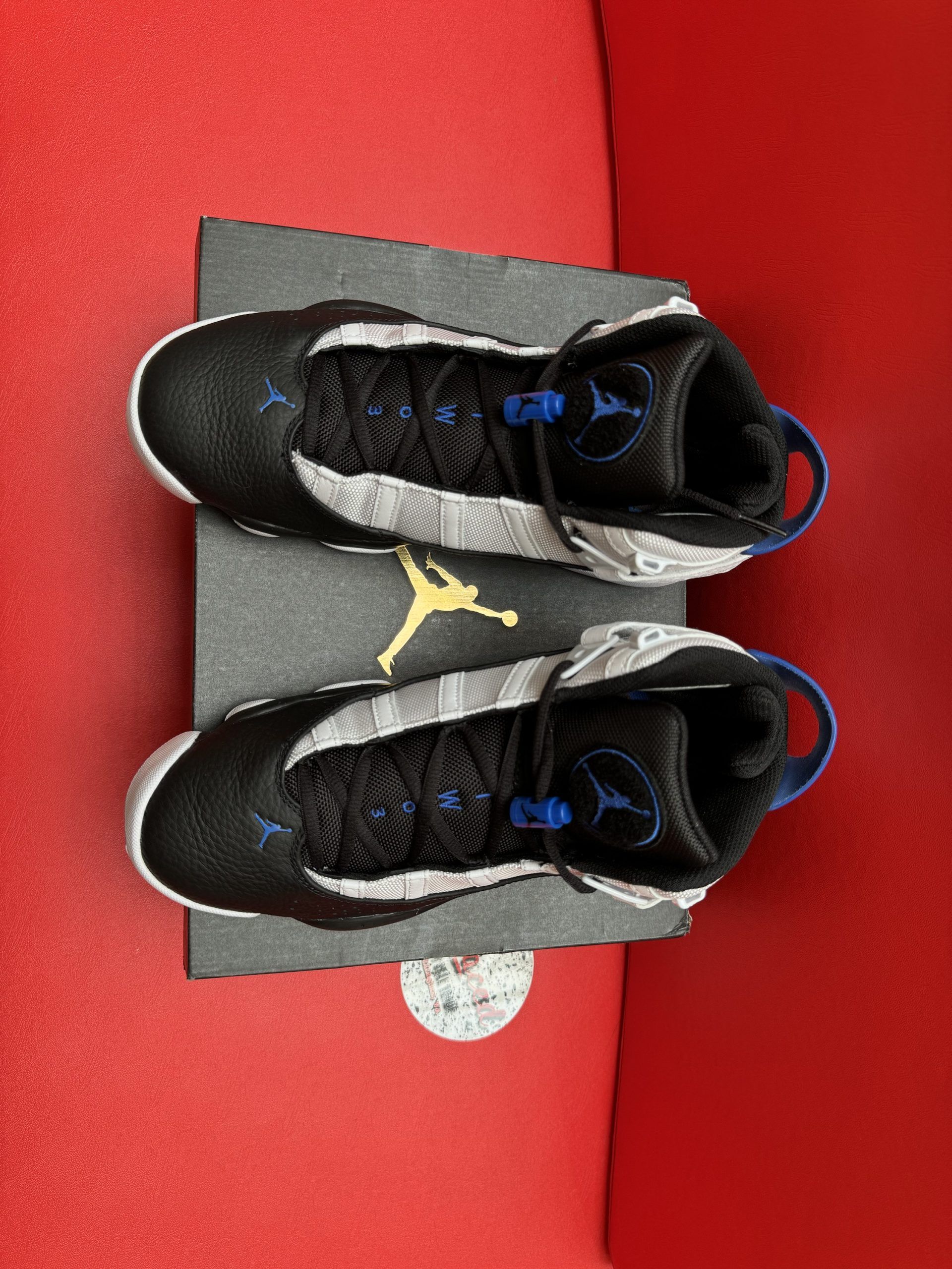 Air Jordan 6 Rings sneakers in black, white, and blue, displayed on a black box, with the sole visible.