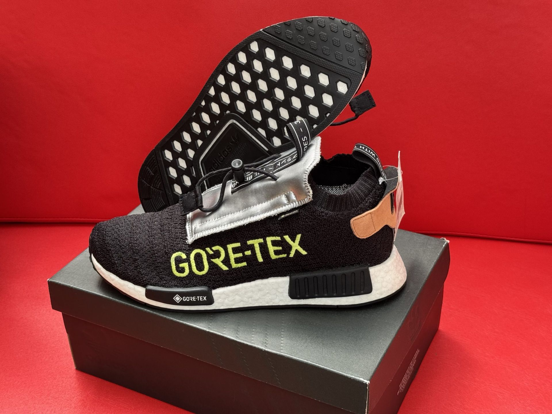 Black and white Adidas NMD Gore-Tex sneaker on a box, with a red background.