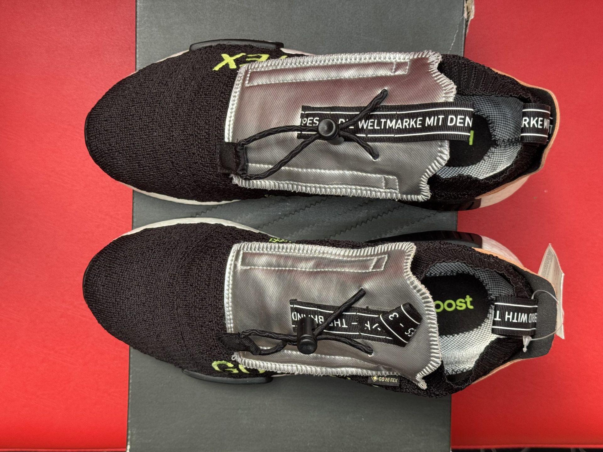 Black and white Adidas NMD Gore-Tex sneaker on a box, with a red background.