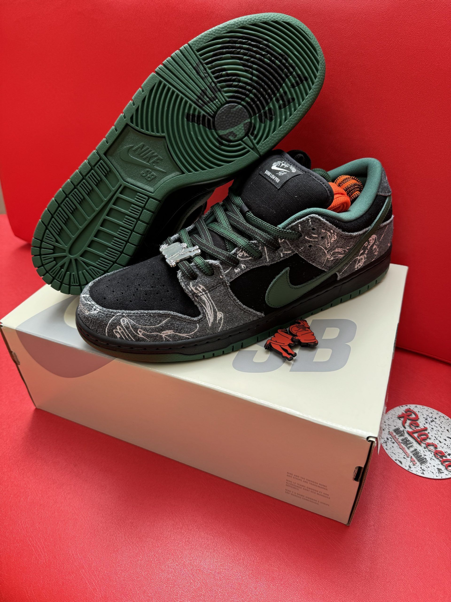 Nike SB Dunk Low sneakers in black and green, displayed with box.