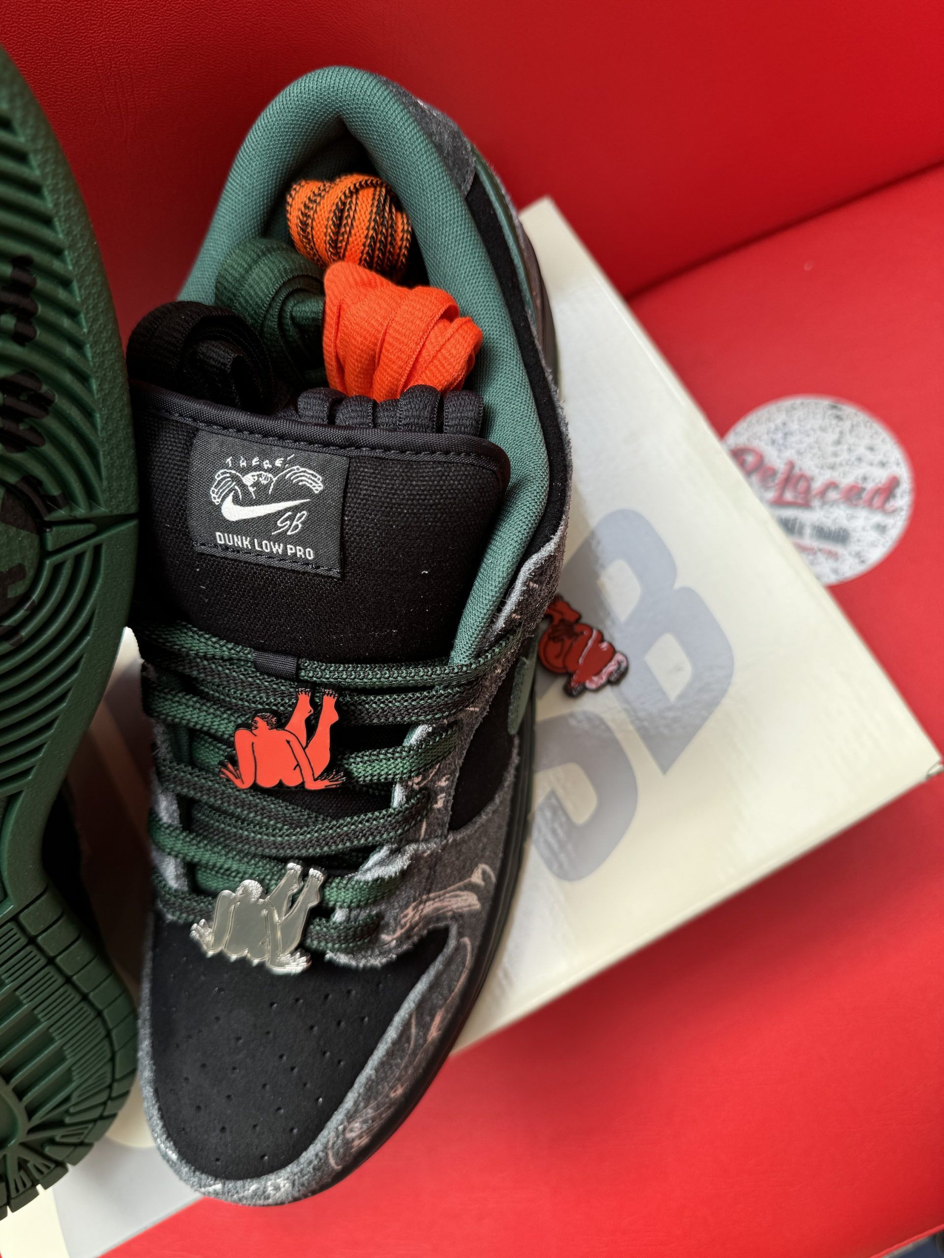 Nike SB Dunk Low sneakers in black and green, displayed with box.