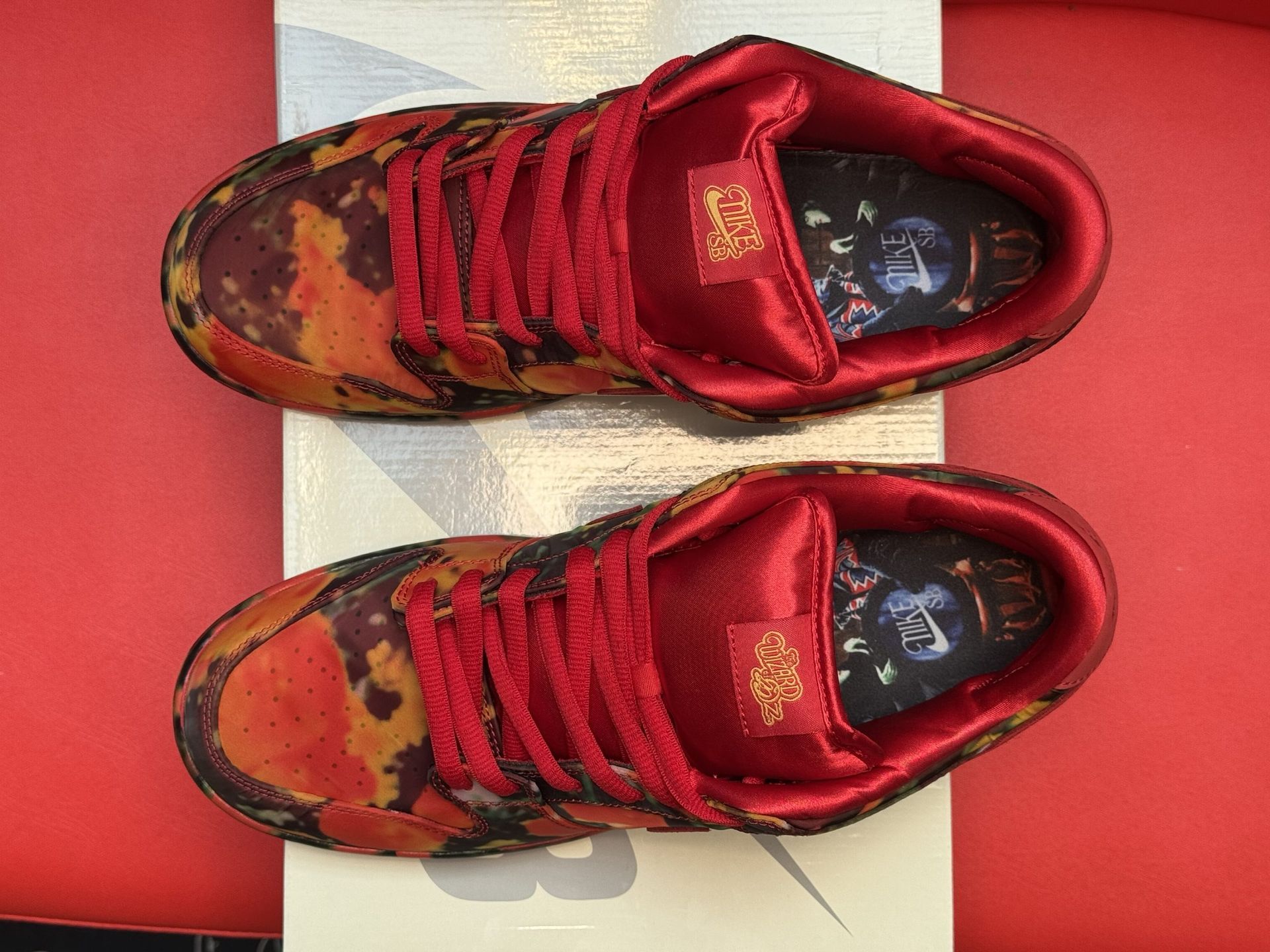 Red and floral patterned Nike Dunk Low sneakers on a white box, red background.