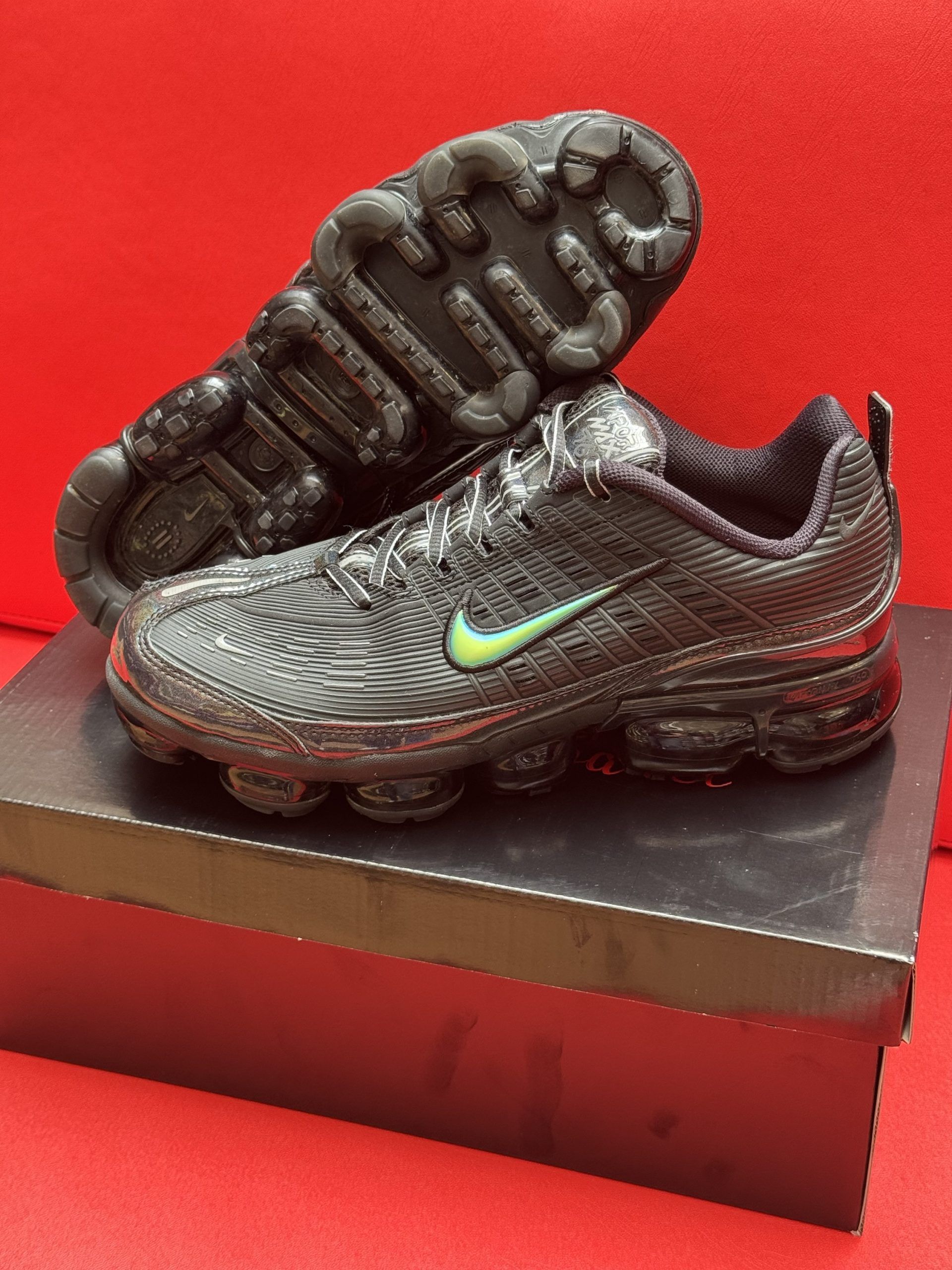 Black Nike VaporMax shoes on a box, green swoosh.