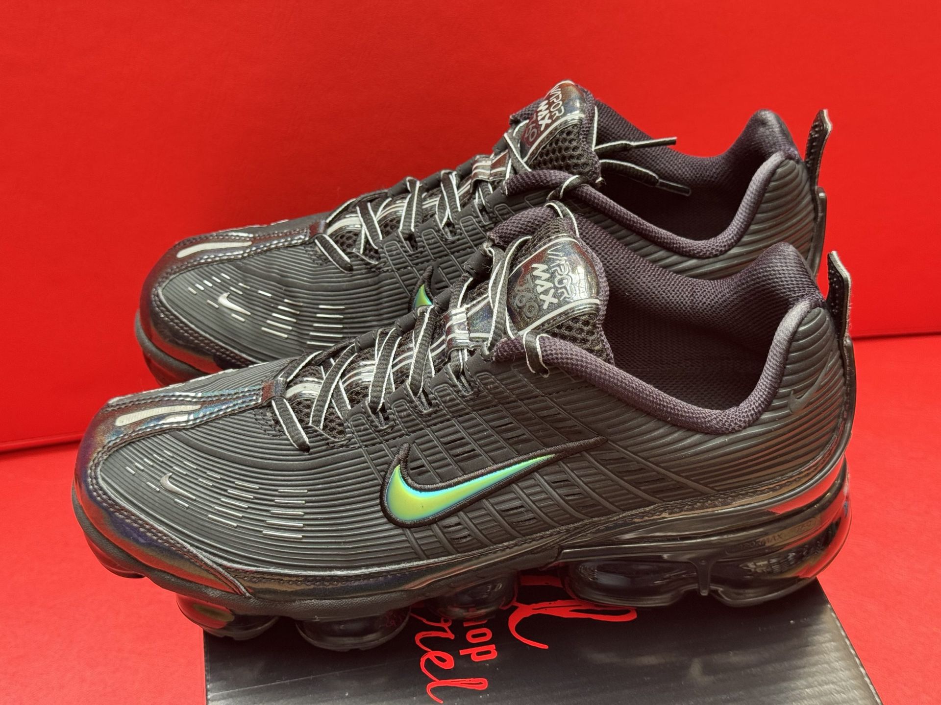 Black Nike VaporMax shoes on a box, green swoosh.